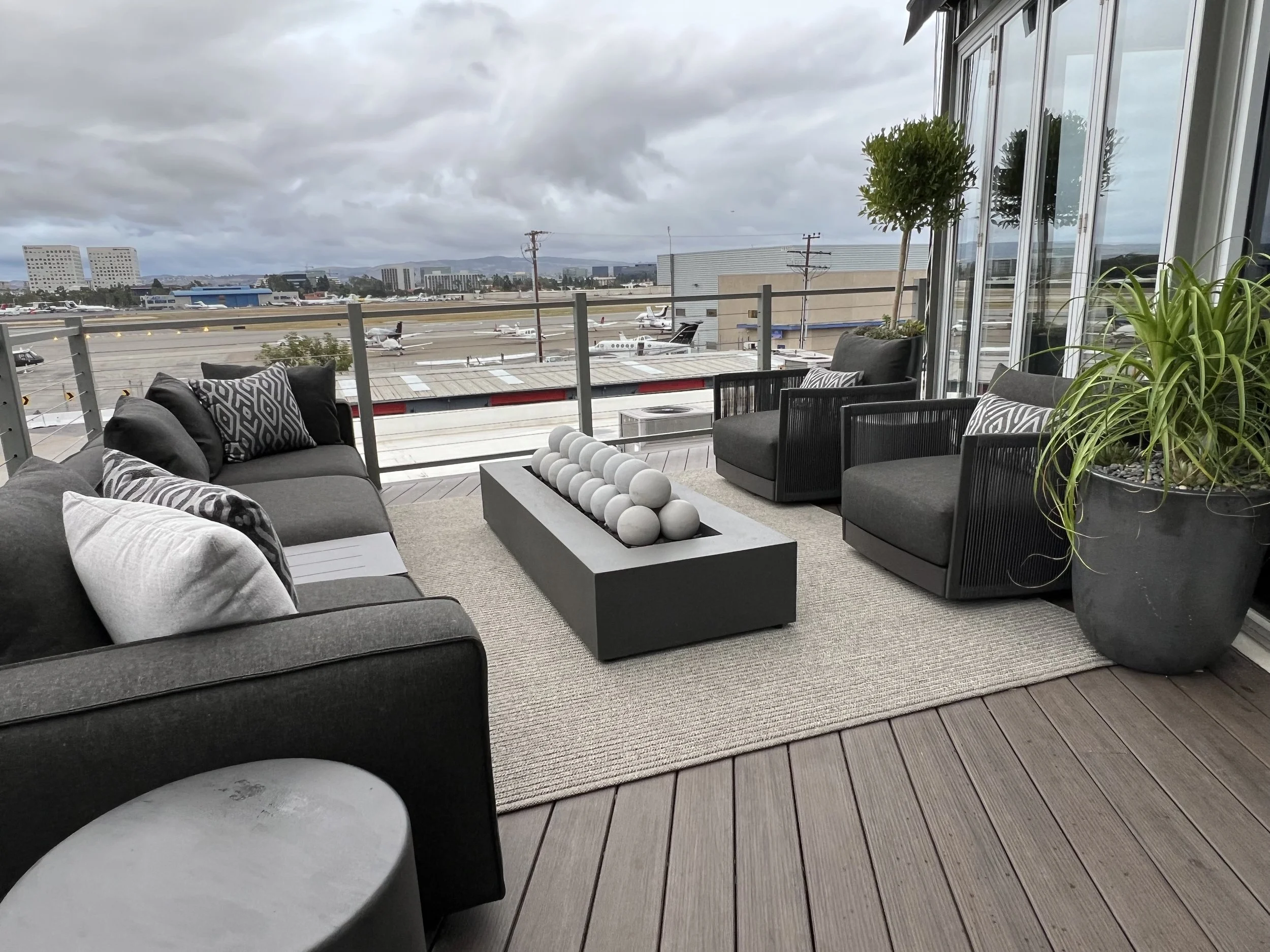 Stylish rooftop terrace with grey outdoor seating, modern decor, and airport runway view