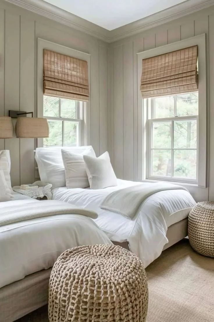 Charming neutral guest bedroom with twin beds, woven ottomans, and soft natural light
