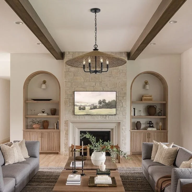 Transitional living room with stone fireplace, wooden beams, arched built-ins, and neutral decor