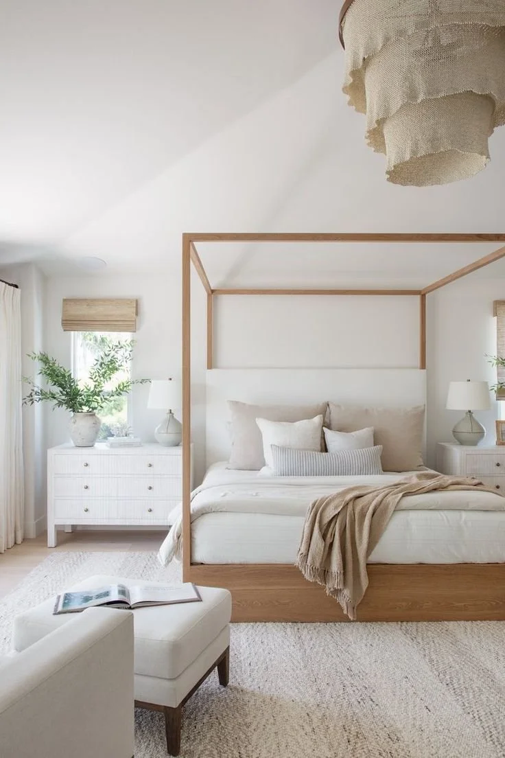 Scandinavian-inspired bedroom with wooden canopy bed, cozy linens, and layered neutral textures