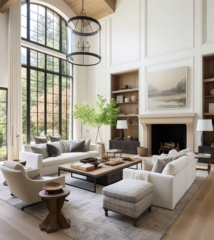 Spacious modern living room with double-height windows, white sofas, and neutral decor accents