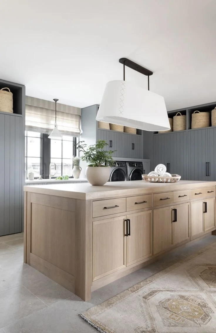 Spacious laundry room with central island, natural wood finishes, and charcoal cabinetry