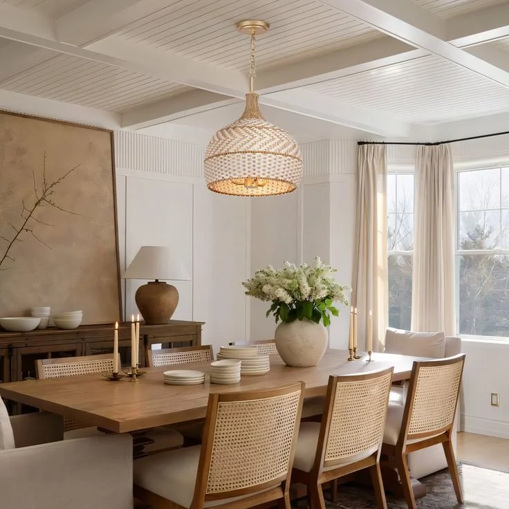 Modern minimalist dining room with light wood furniture, woven chairs, and oversized botanical art