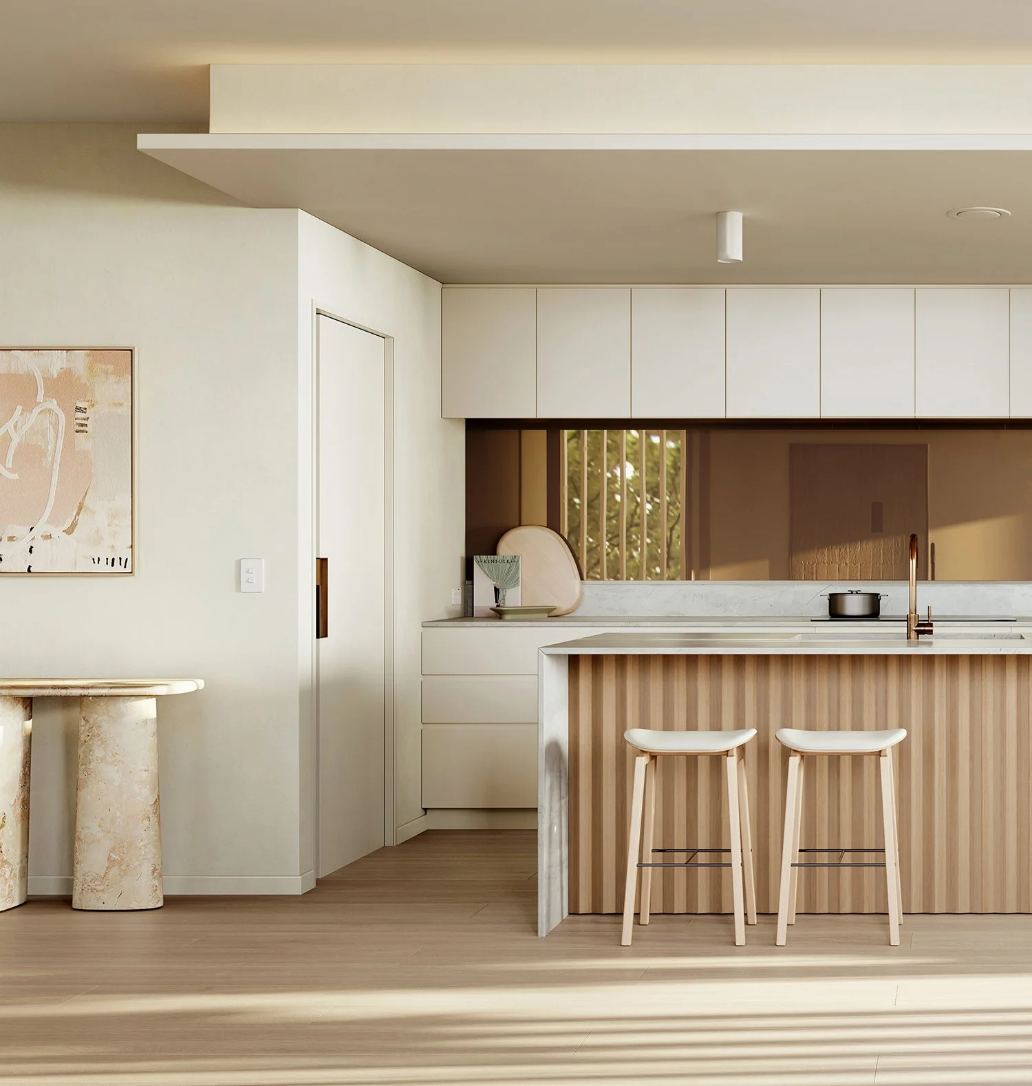 Modern kitchen with white cabinetry, a marble island with wooden paneling, two white bar stools, and a small workspace with decorative items and window in the background.