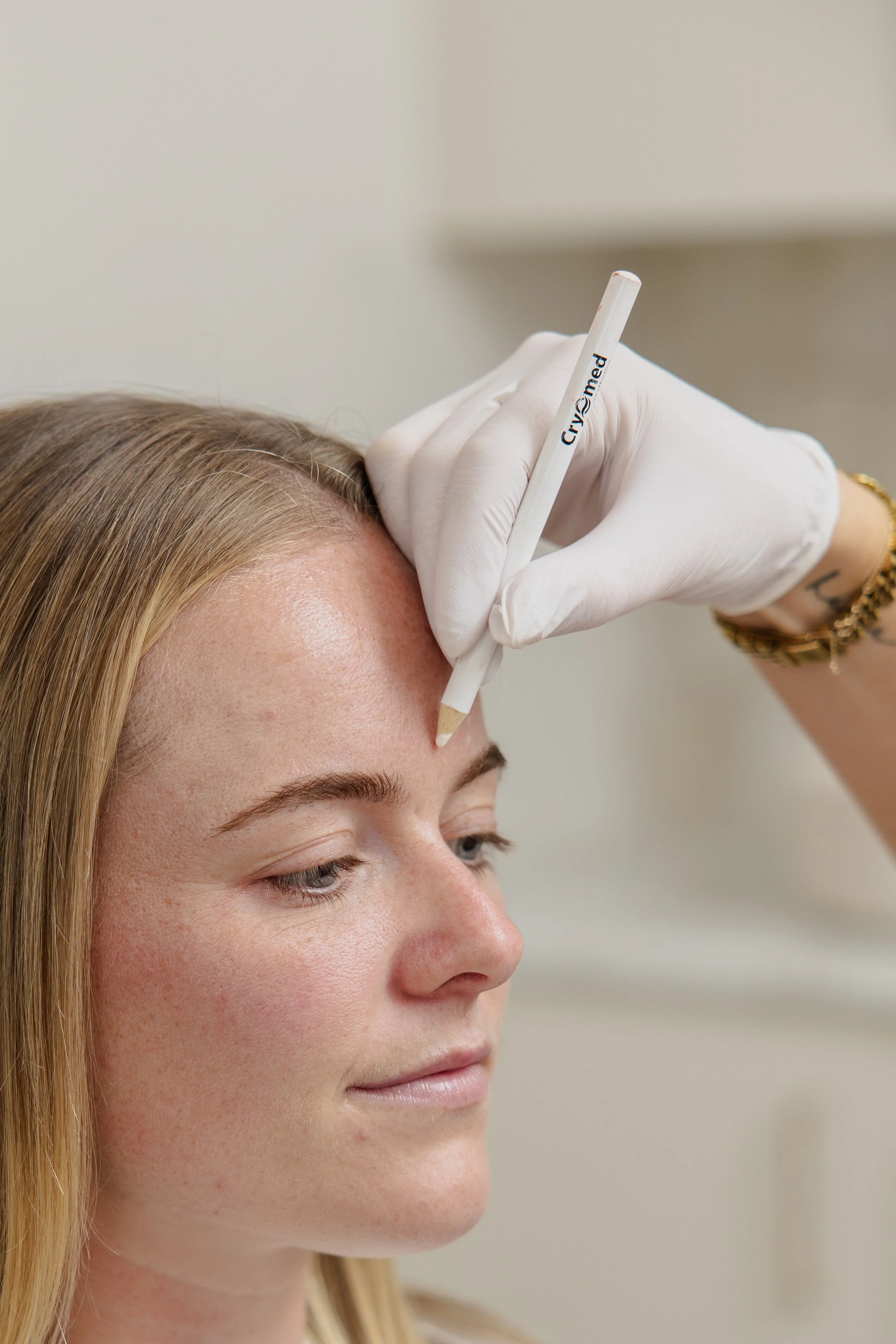 A woman receiving an injection in her cheek from a medical professional wearing gloves in a clinical setting.