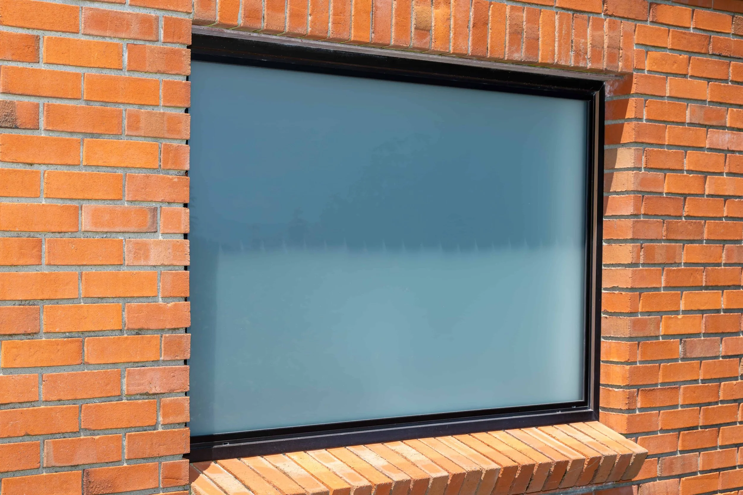 External view of a bronze aluminium window that Eversure has double glazed with frosted glass. reFIT Ali service