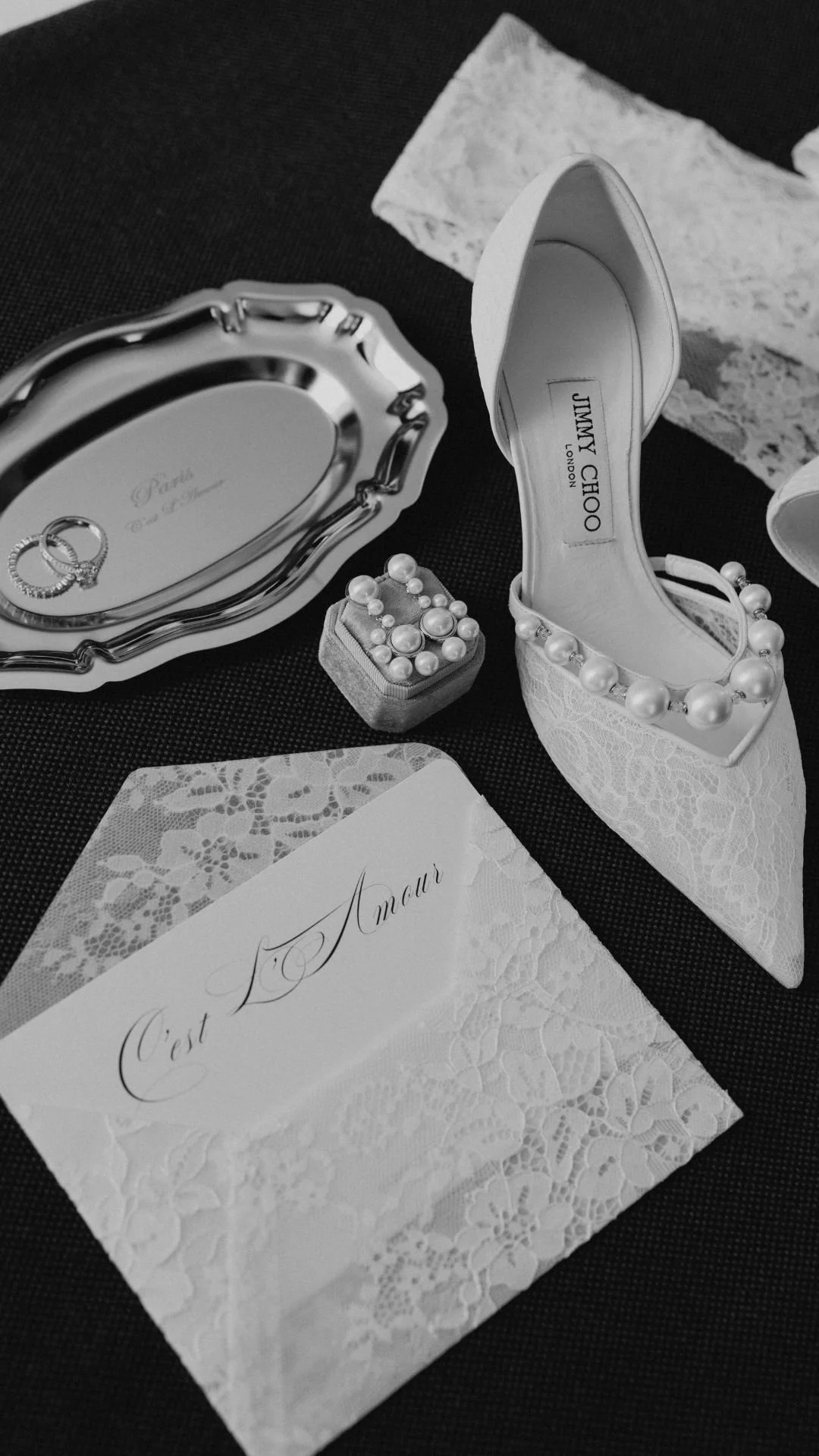 Luxury Jimmy Choo bridal details featuring pearly jewellery, lace wedding shoes and lace gloves, wedding rings.