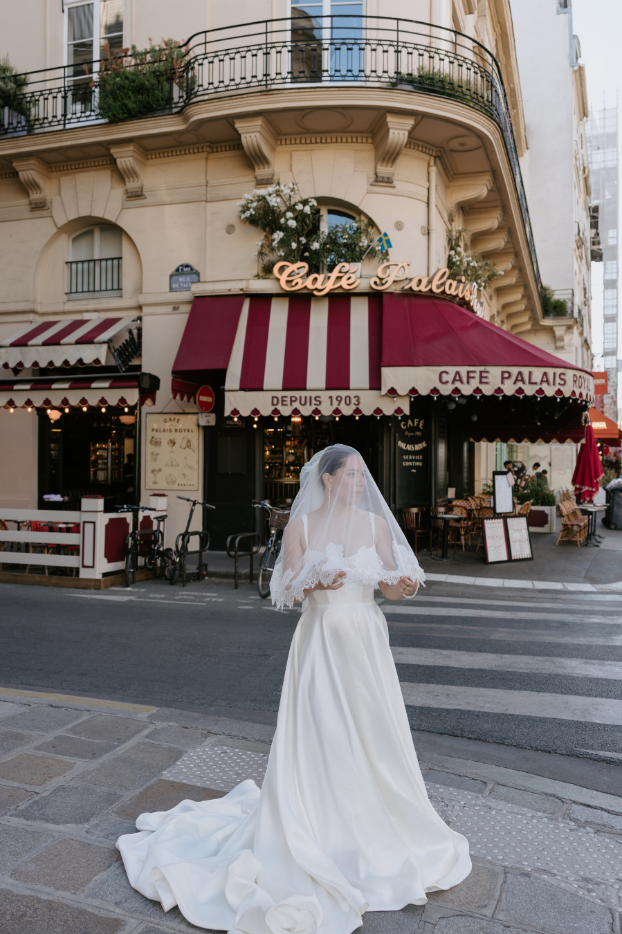 Bride in white wedding gown and veil outside Cafe de la Paix in Paris, France