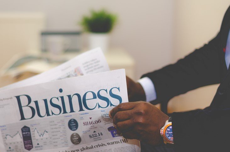 Person holding business section of newspaper, for those needing help editing a professional business plan