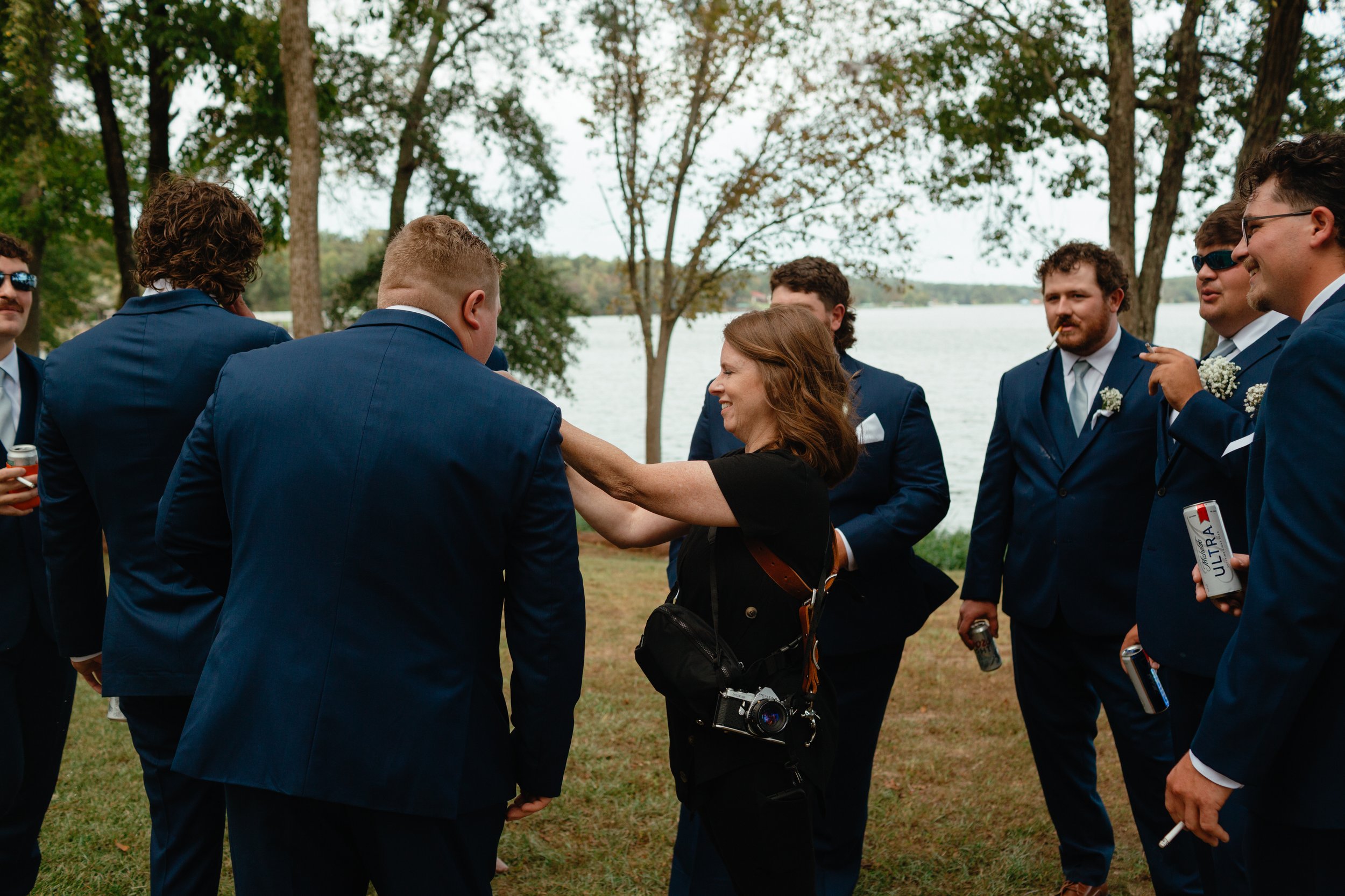 Wedding photographer helping groomsmen