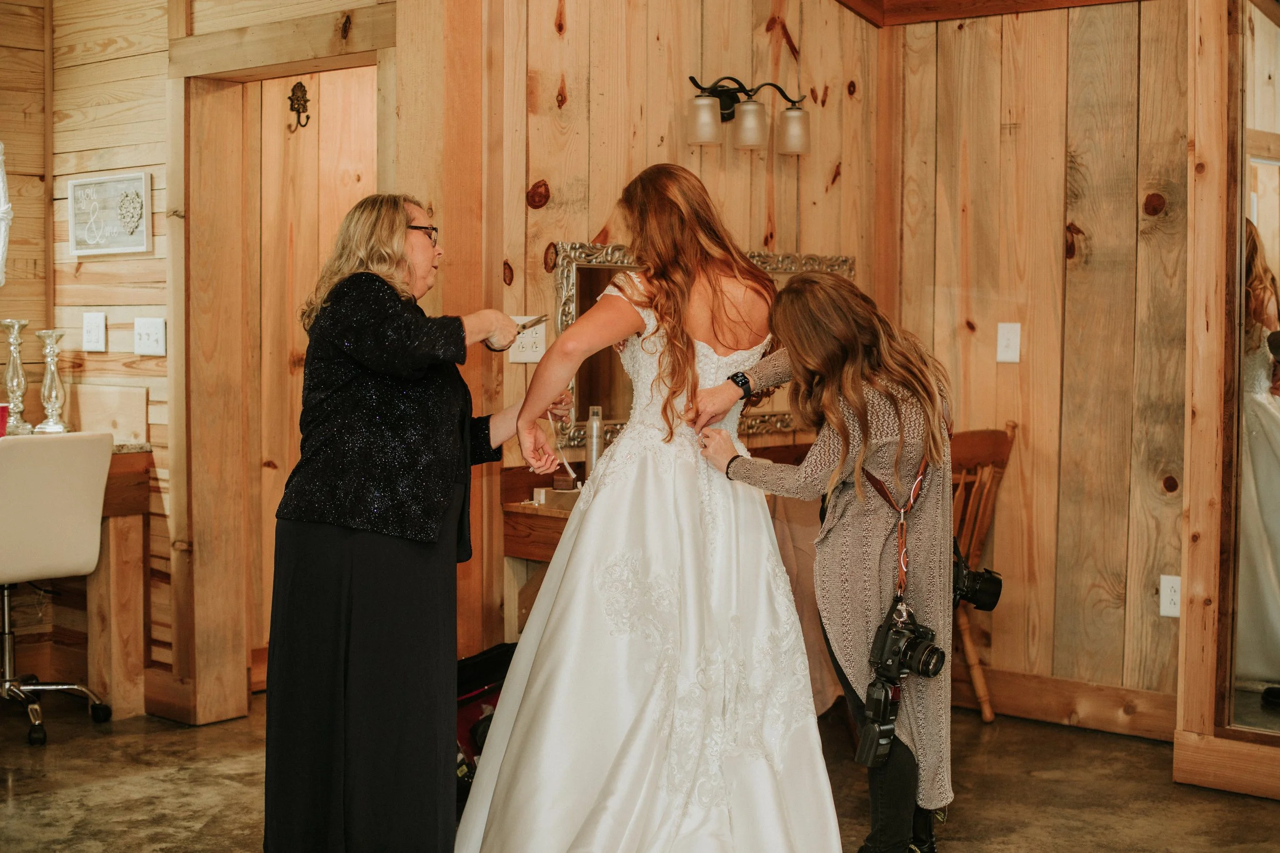 Wedding photographer helping bride zip her dress