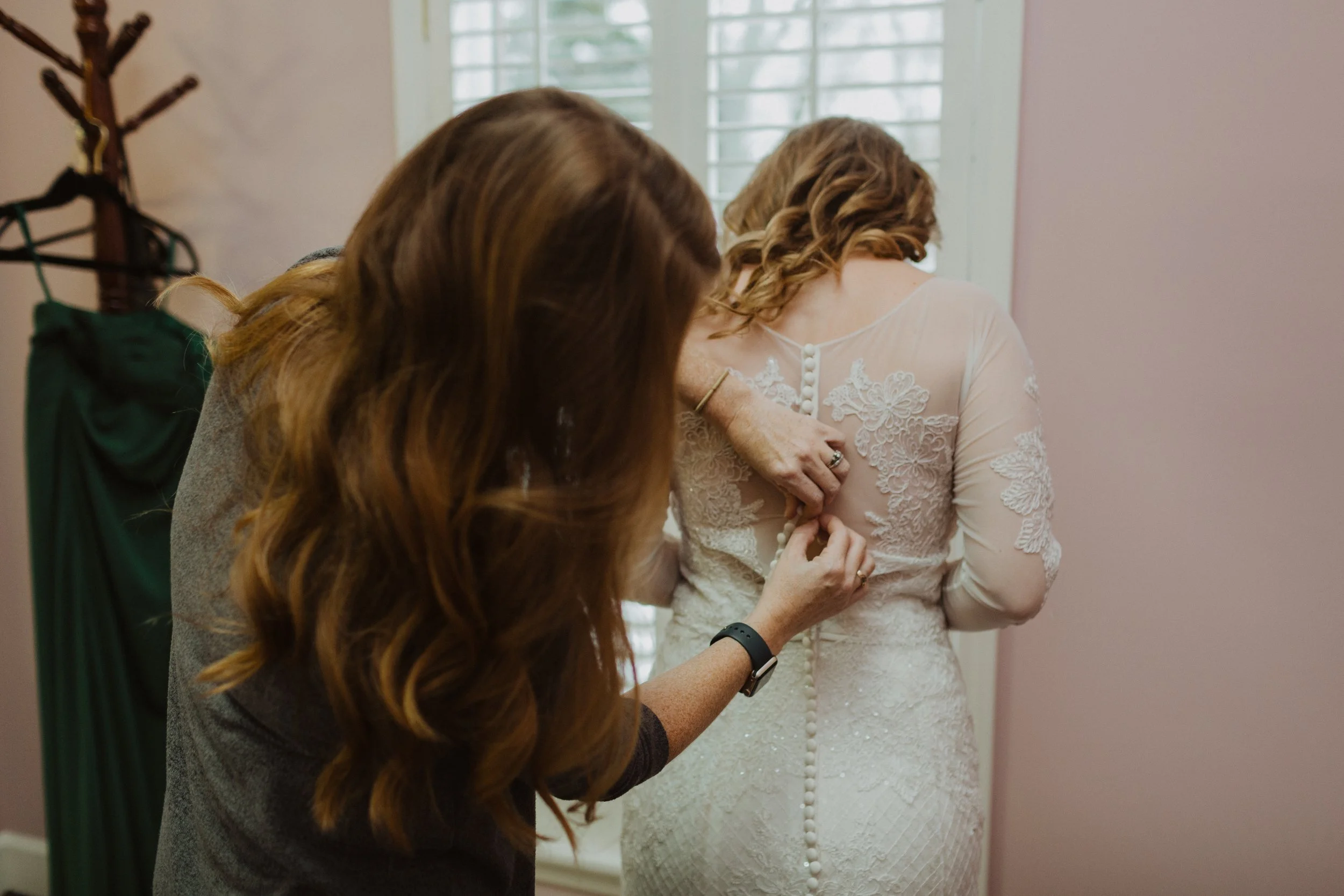 Alabama wedding photographer buttoning up brides gown