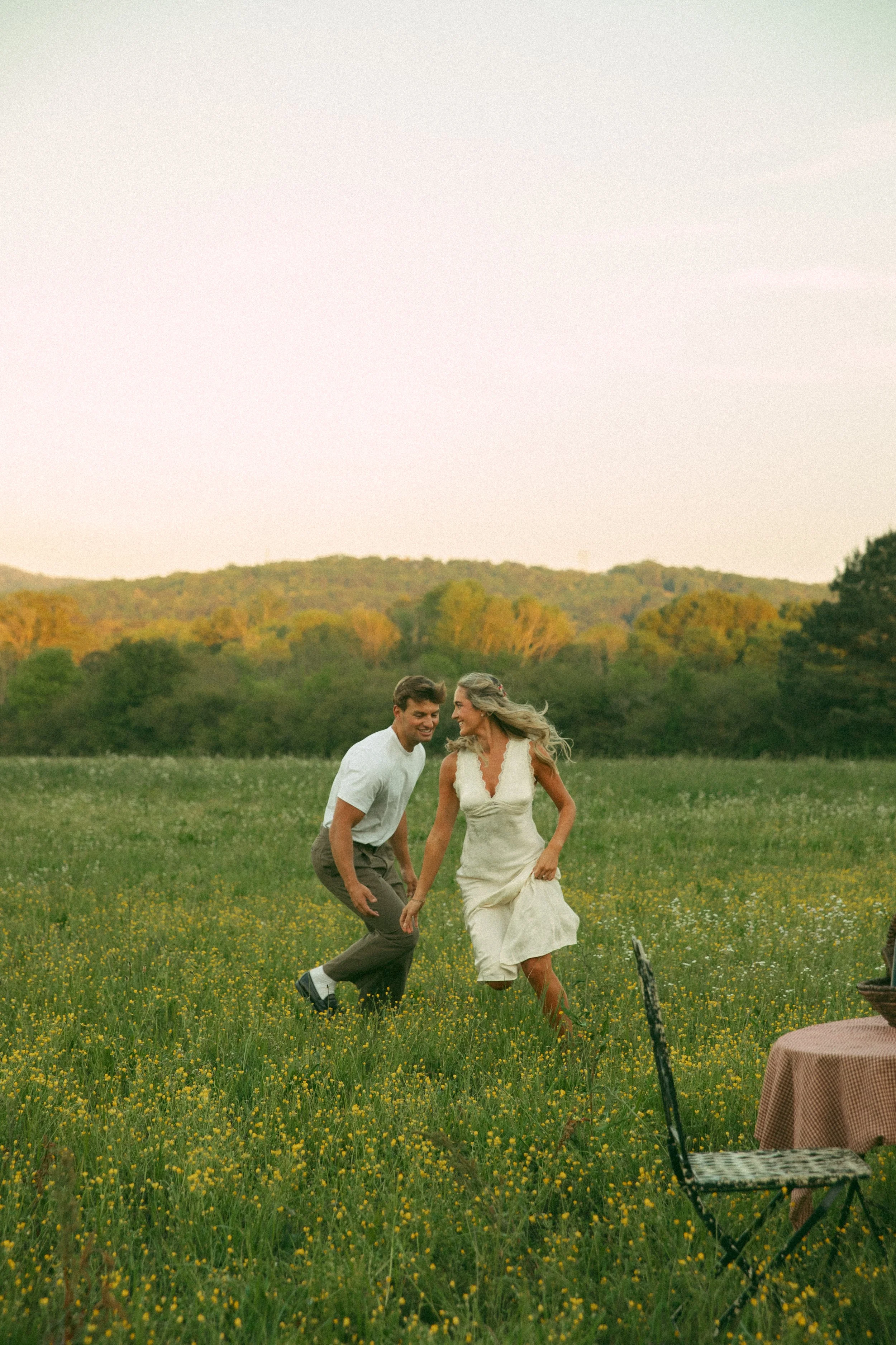 couple chasing each other in a field in oxford alabama with mountain view