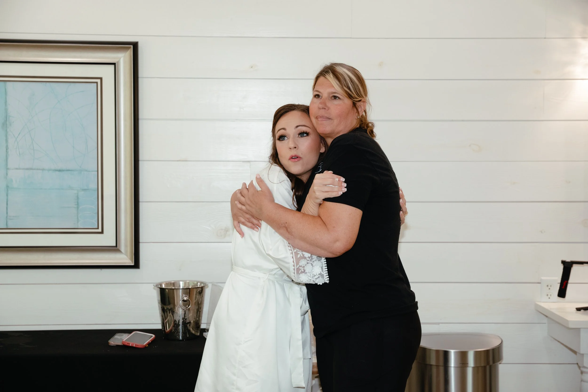 A wedding coodinator hugs a bride before she gets into her dress at Oak Meadow Event Venue.