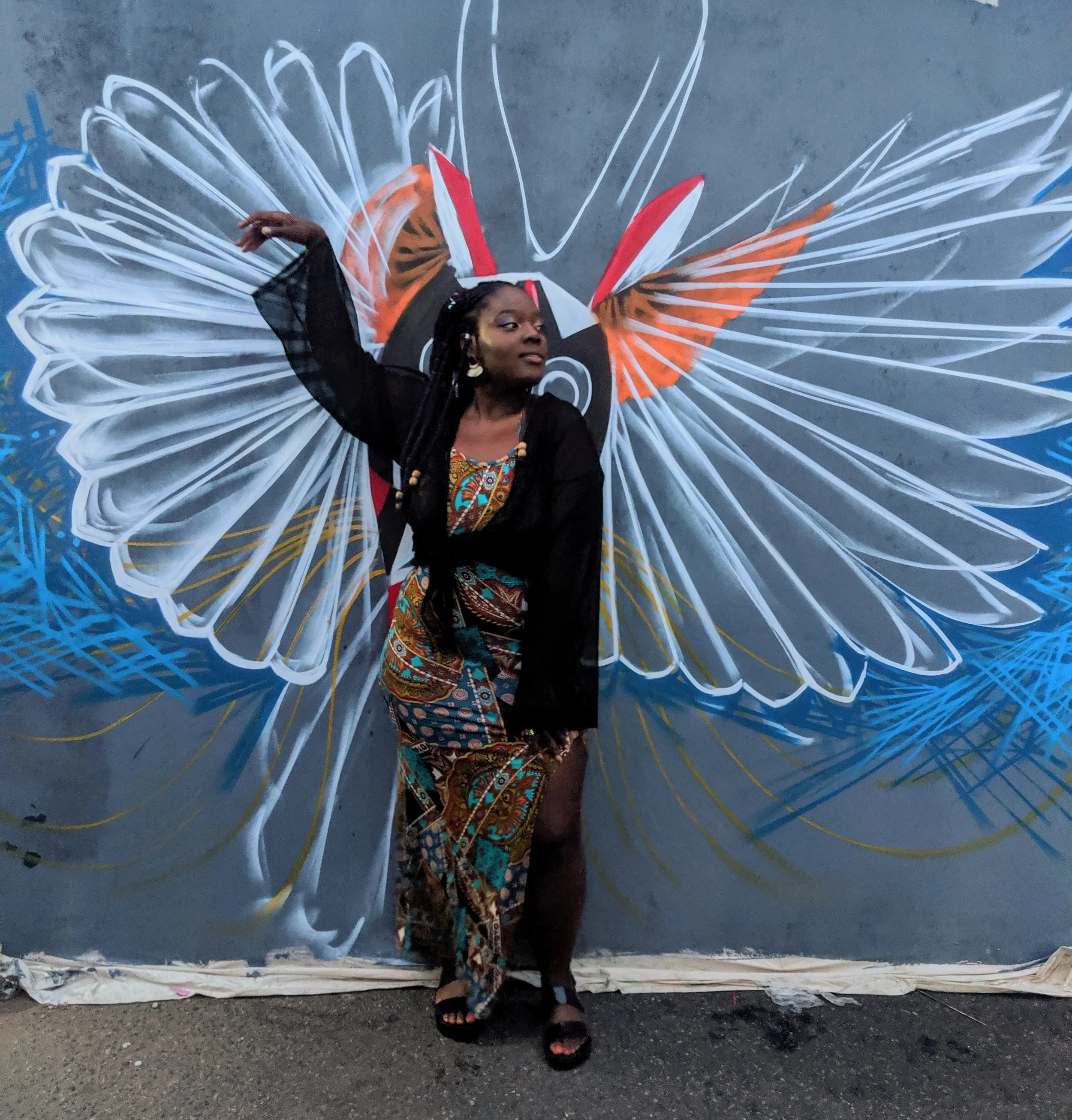 Leonie, Ella Travel Ghana advisor, posing in front of a blue butterfly mural.