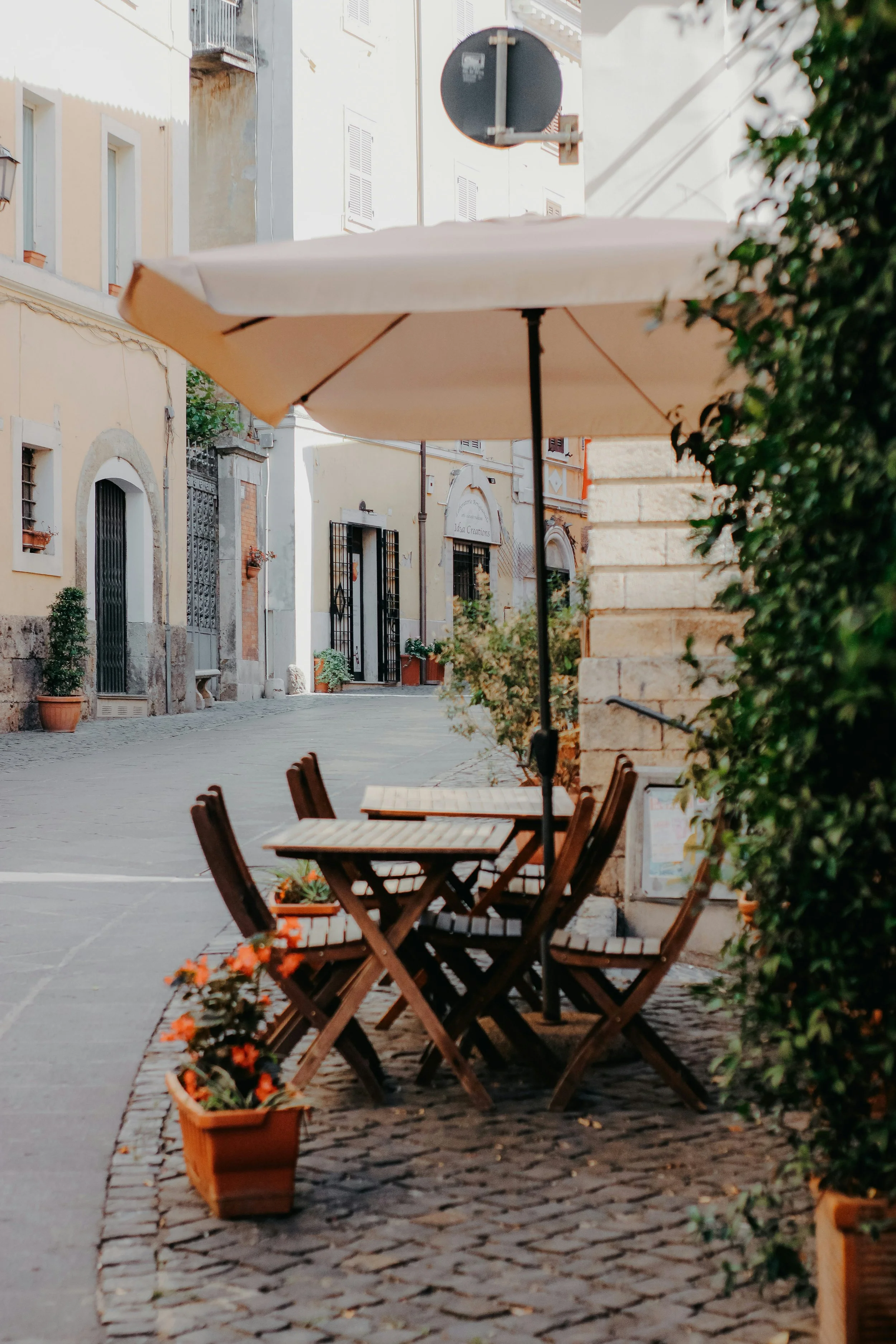 Photo of a couple small tables outside a restaurant on a small street in rome