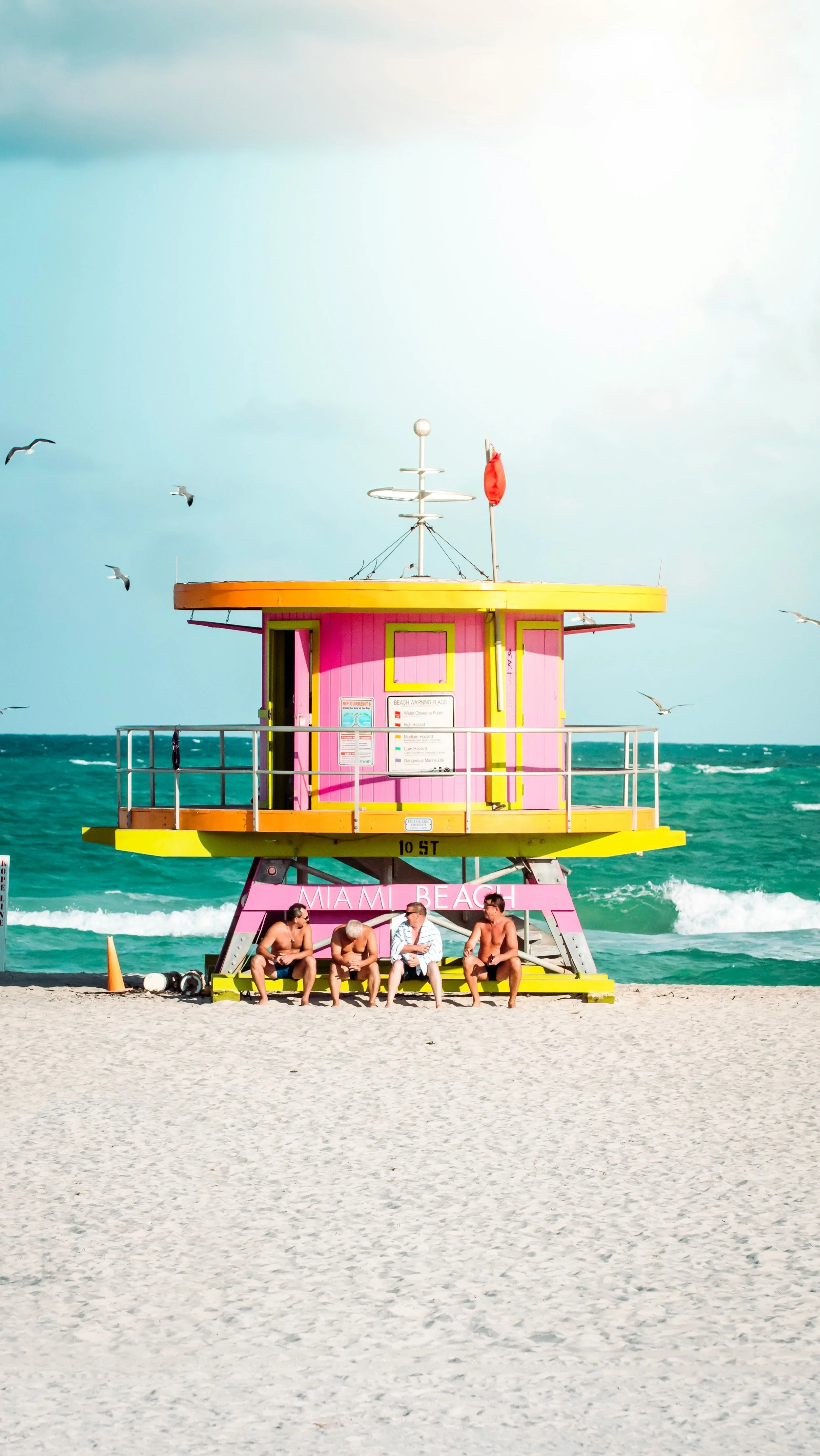 Four locals hanging out on one of Miami Beach's  pink lifeguard stands on south beach
