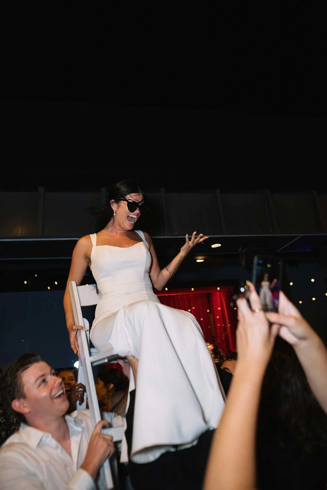 non-traditional wedding bride being lifted in a chair on the dance floor