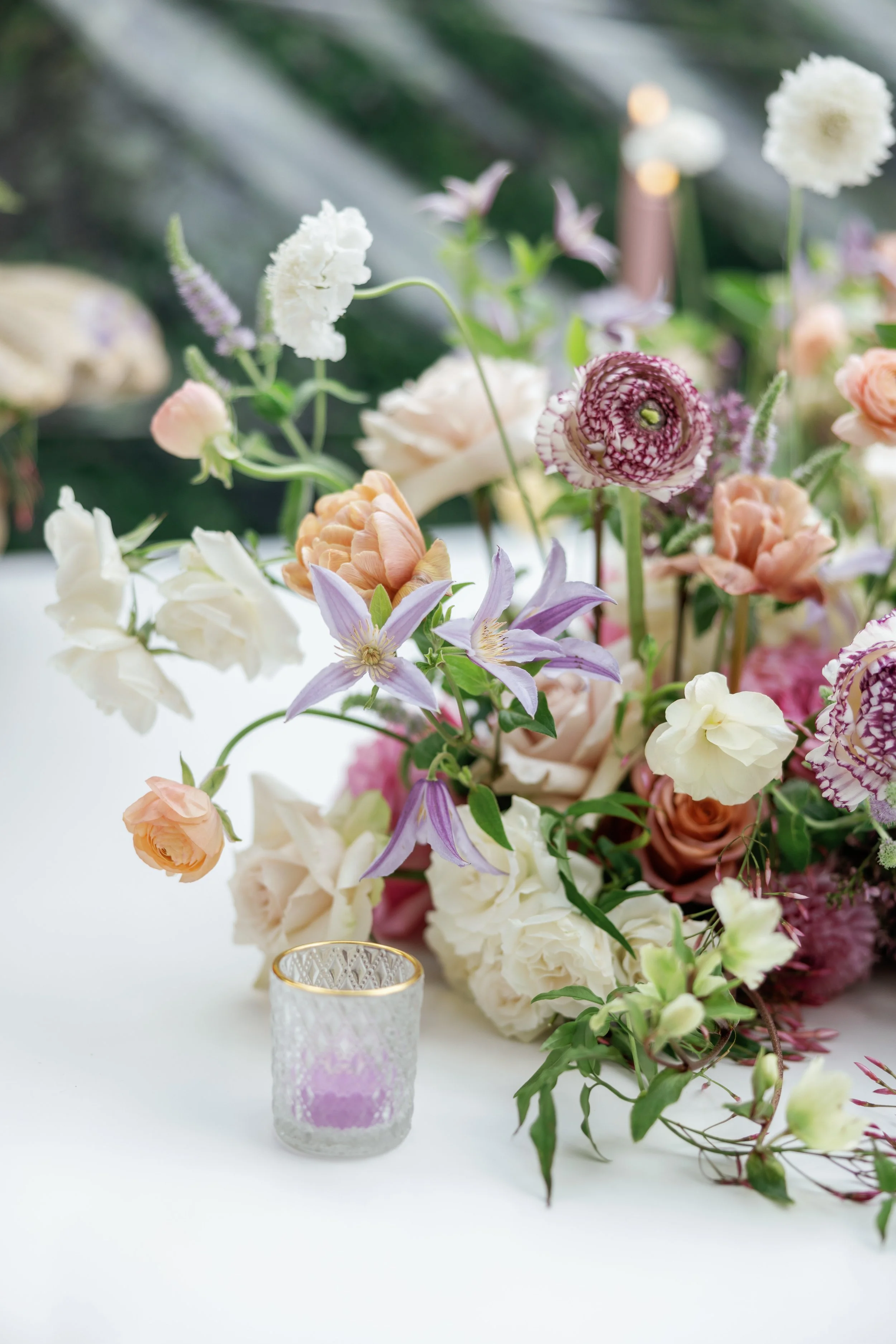 Close-up of layered wedding florals with soft blush, lilac, and textured blooms in elevated wedding design