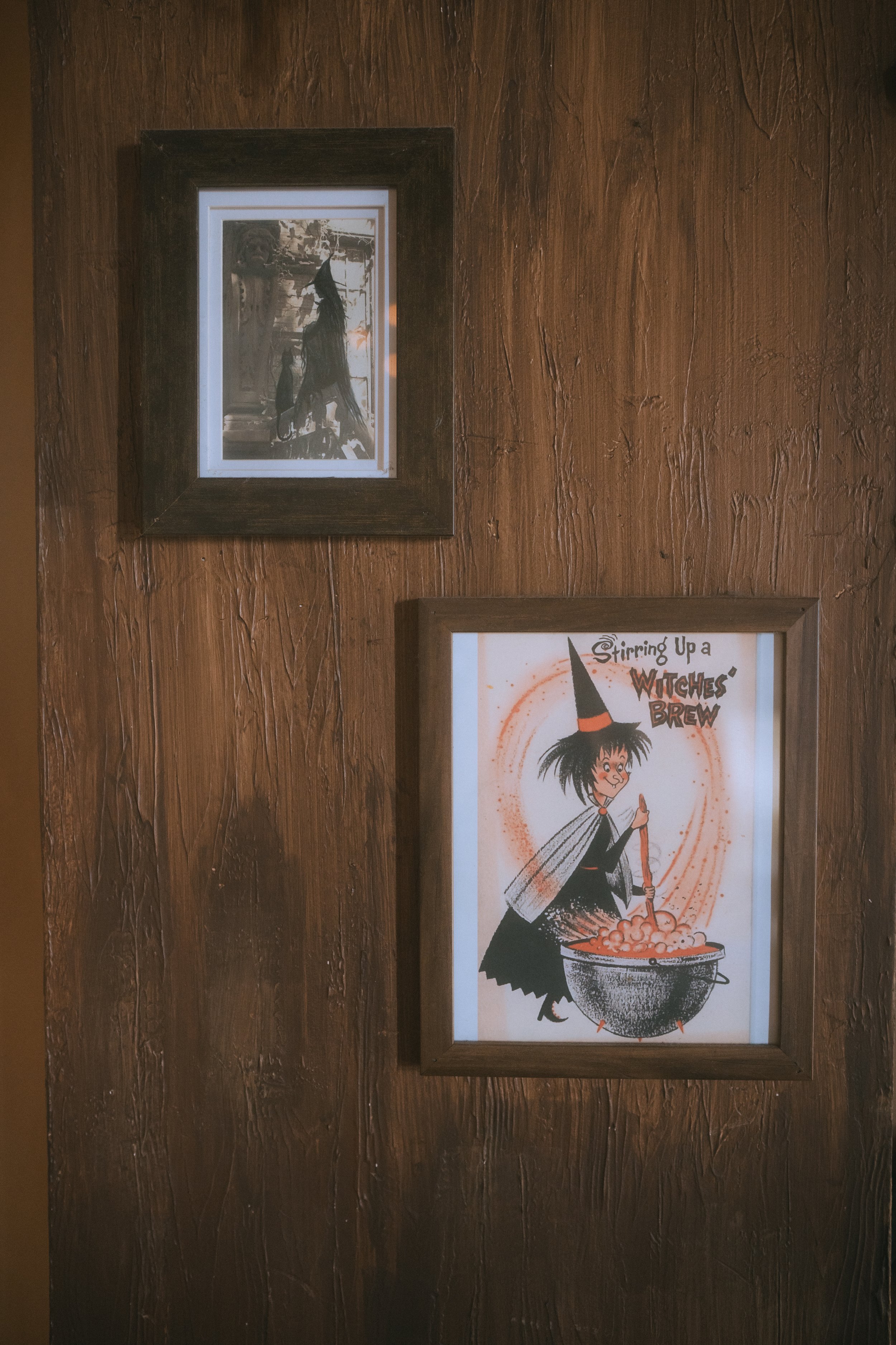 Framed vintage-style witch artwork displayed on wood wall as part of a non-traditional wedding decor setup