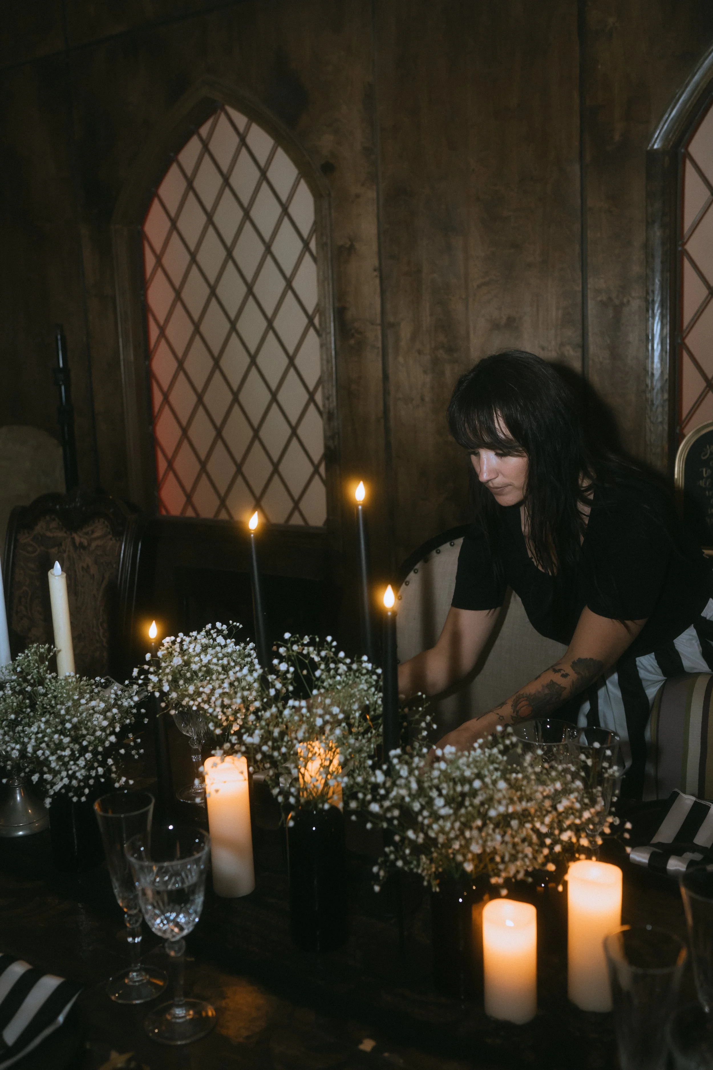 Wedding planner arranging a candlelit wedding table with baby’s breath centerpieces and black taper candles