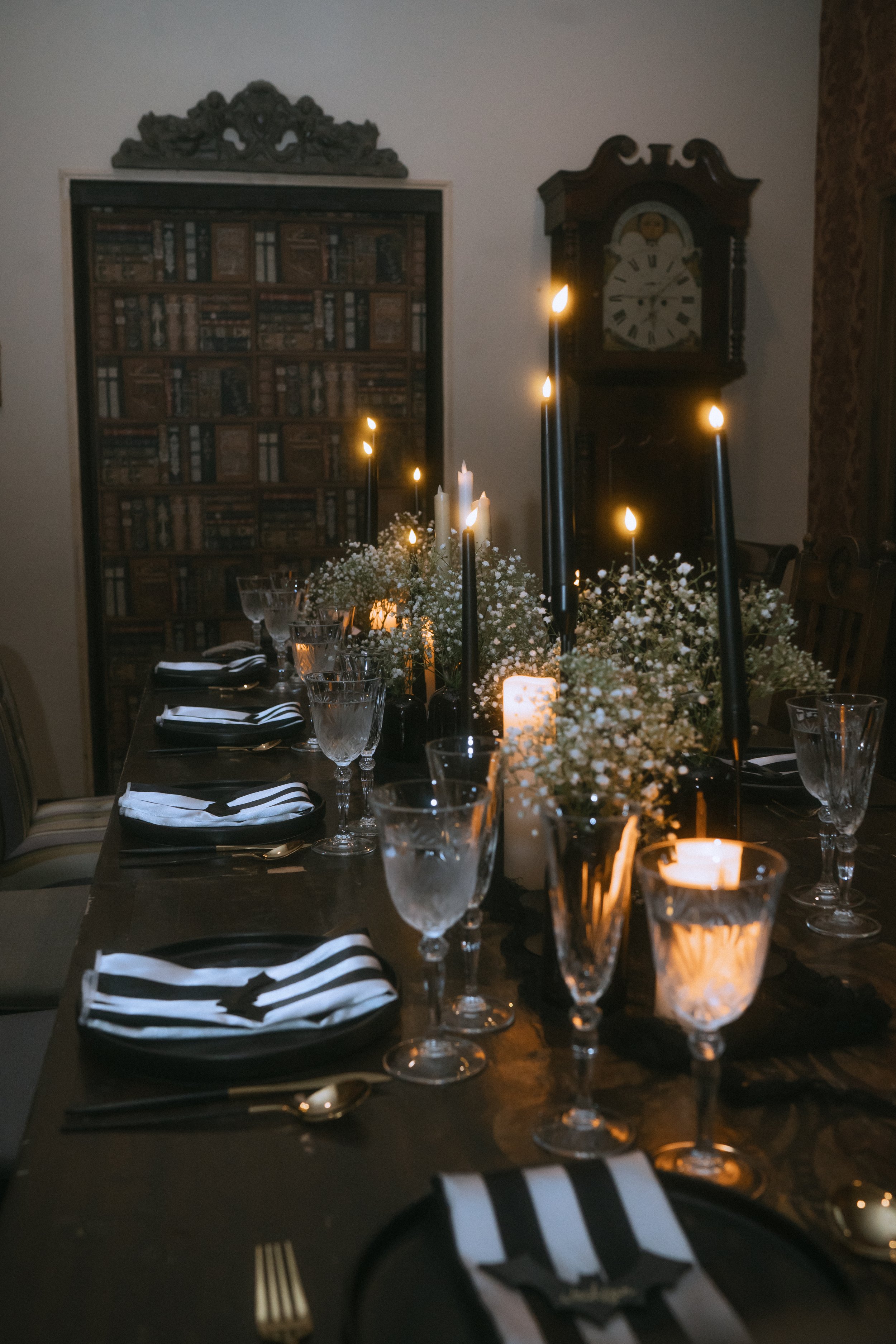Long wedding reception table with black taper candles, baby’s breath centerpieces, and black-and-white place settings