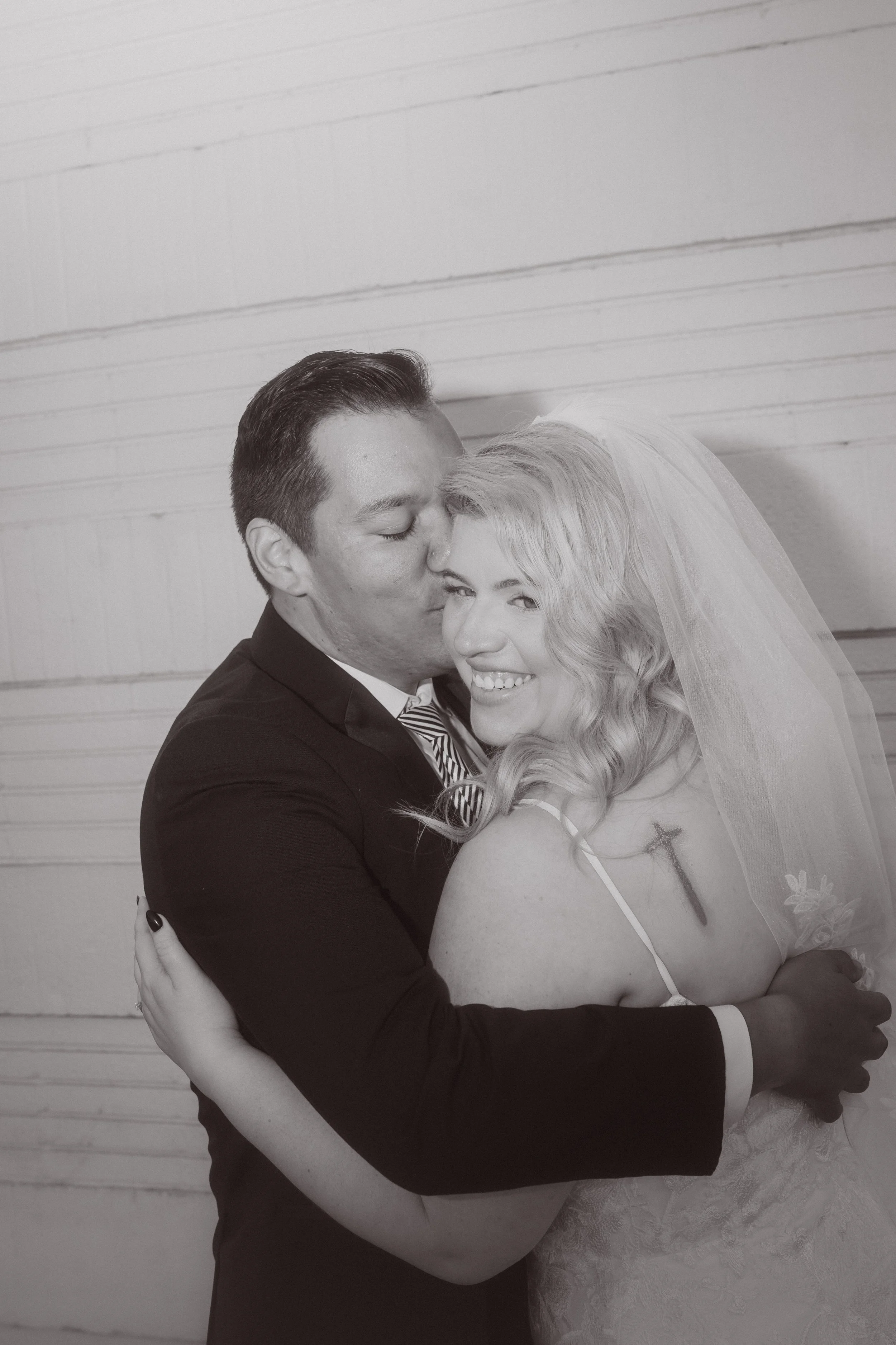 Black and white portrait of bride and groom embracing, smiling during an intimate wedding moment
