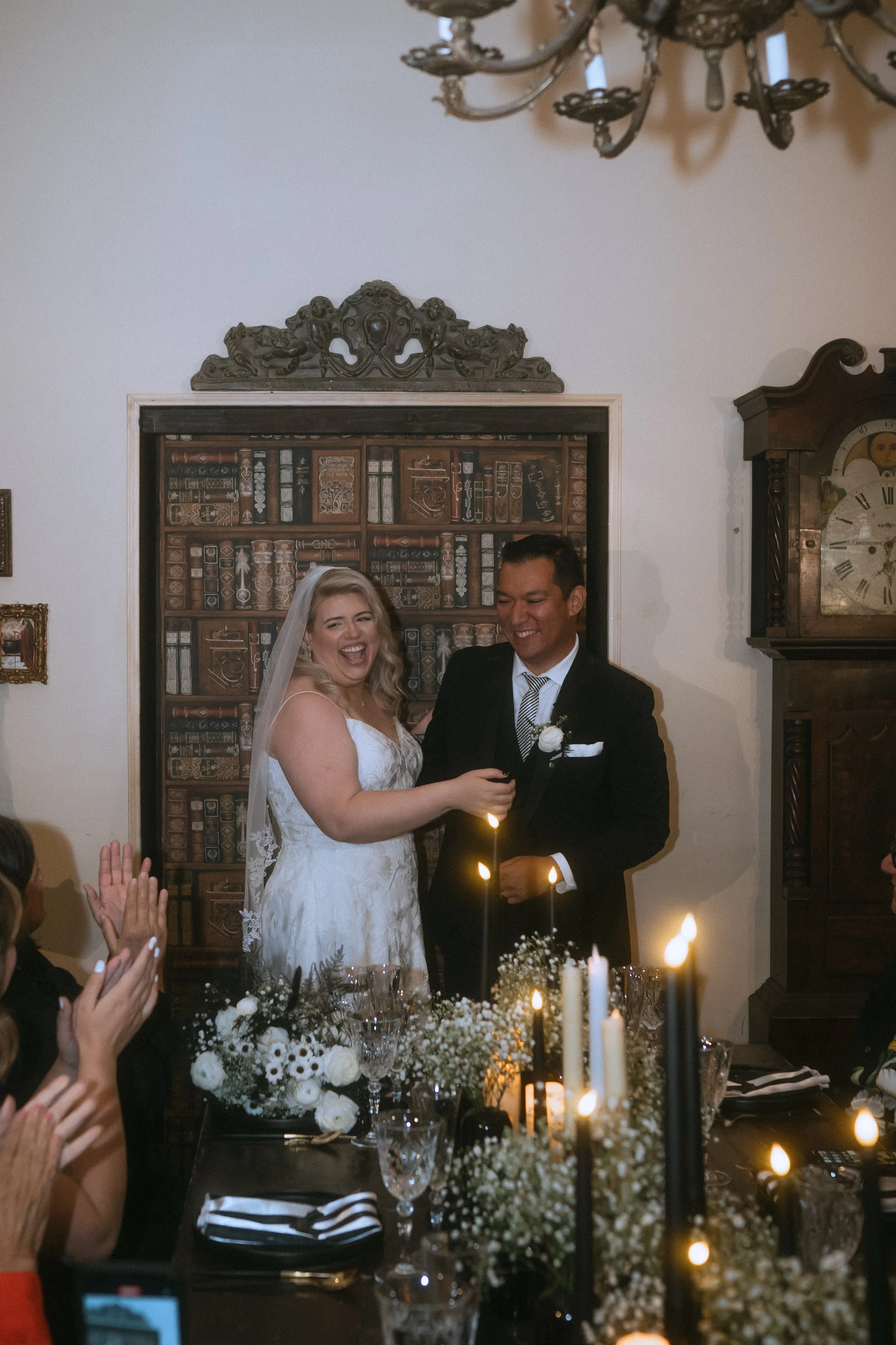 Bride and groom laughing together during an intimate candlelit wedding reception with floral centerpieces