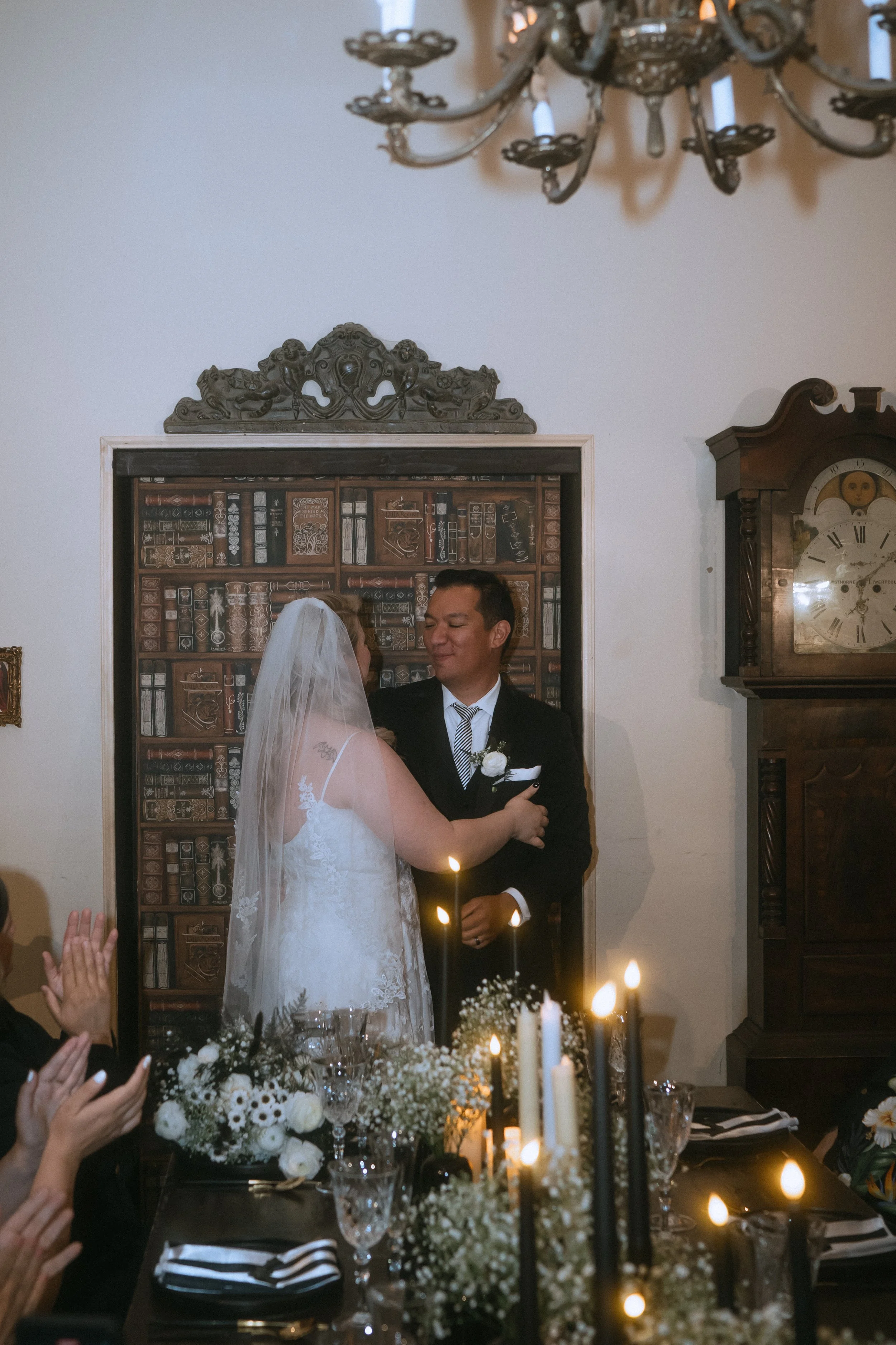 Bride and groom embracing during an intimate wedding reception surrounded by candlelight and floral decor