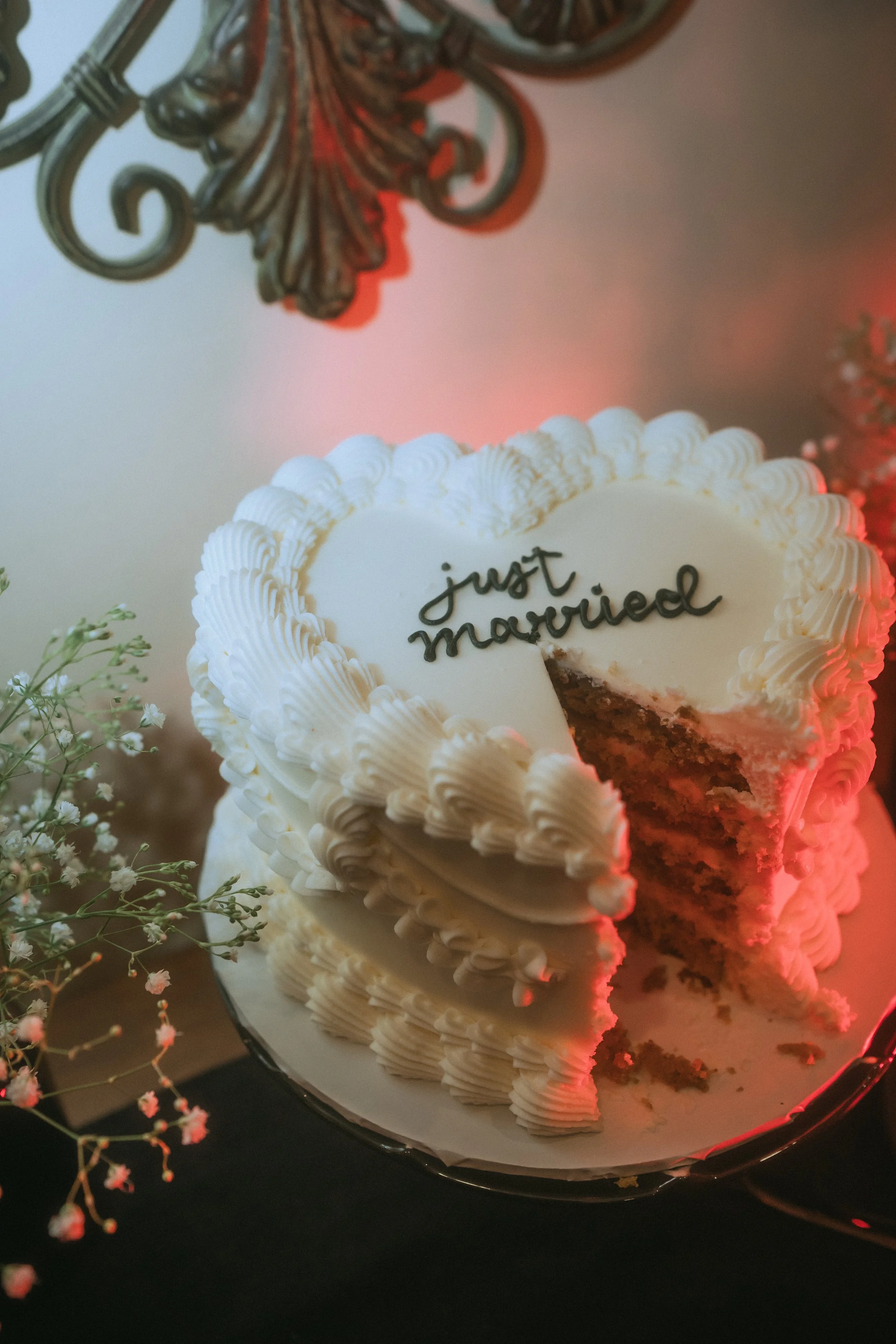 Close-up of wedding cake with slice removed and “just married” written on top with soft candlelight glow