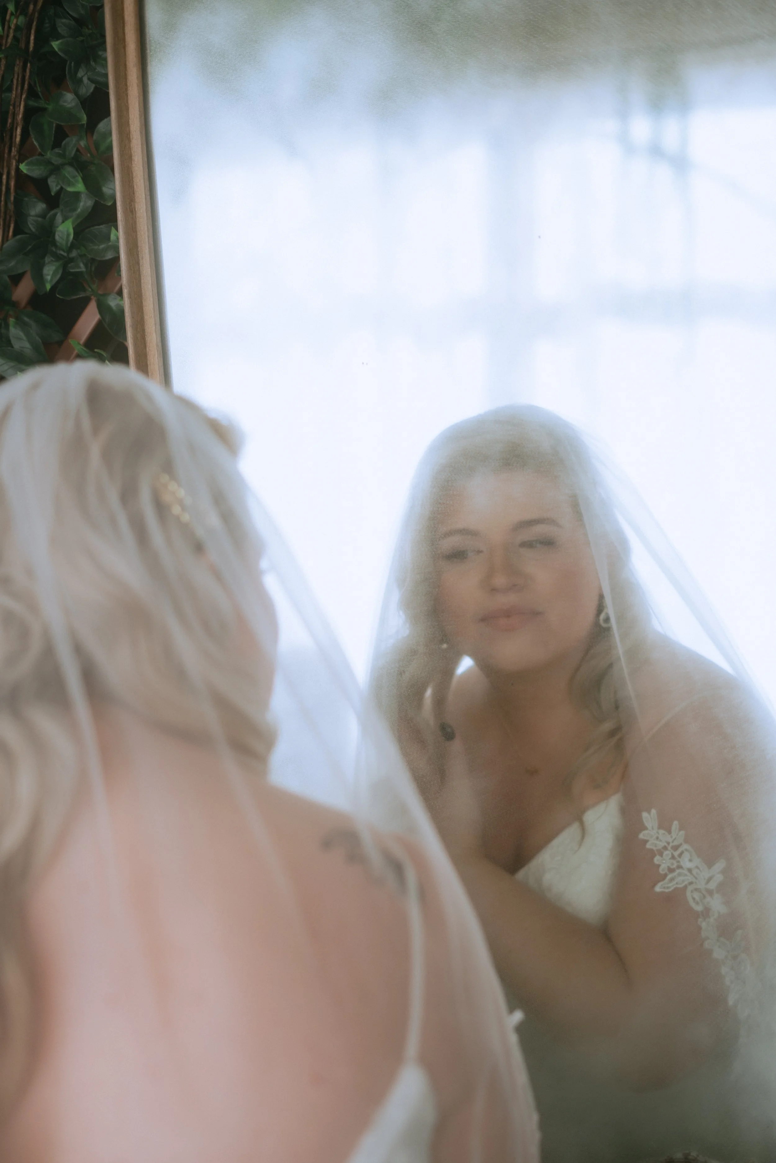 Bride reflected in a mirror wearing a veil during a soft, romantic wedding getting ready portrait