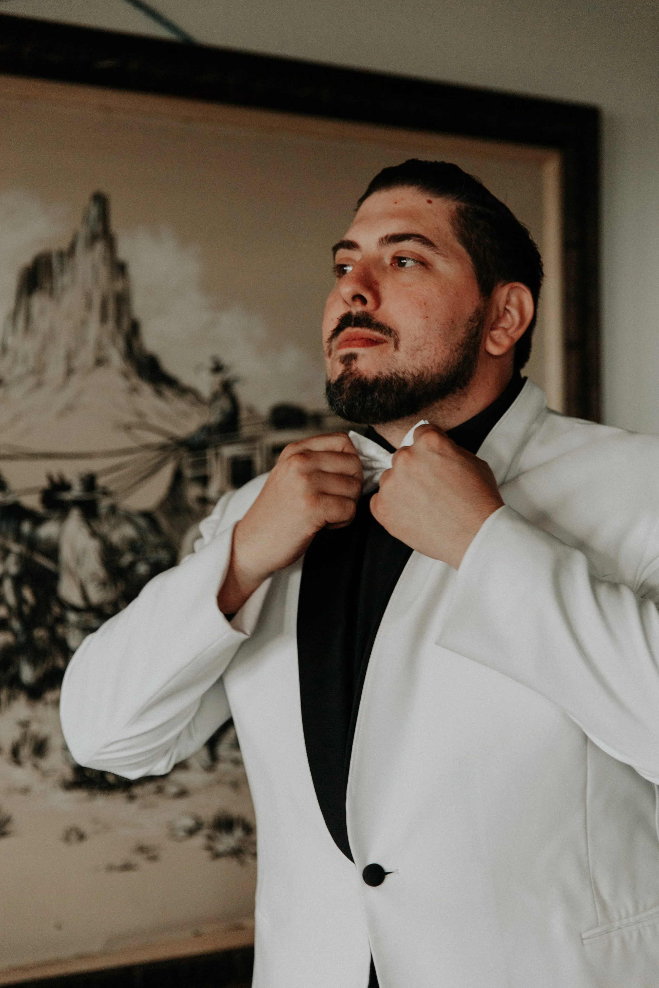 Groom adjusting his bowtie while getting ready for wedding ceremony