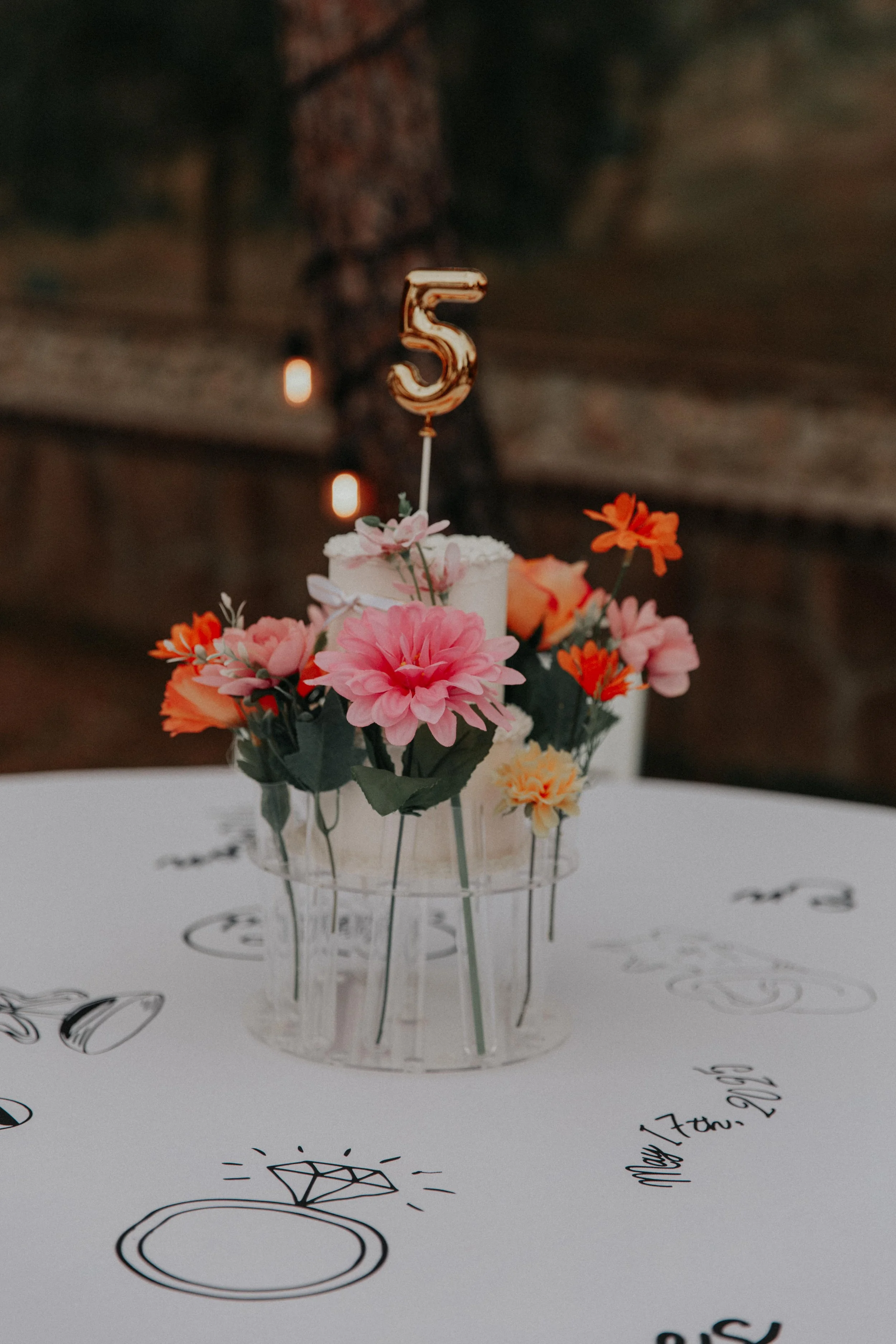 Bold colorful wedding table decor with playful floral centerpiece, mini cake, and illustrated reception table details