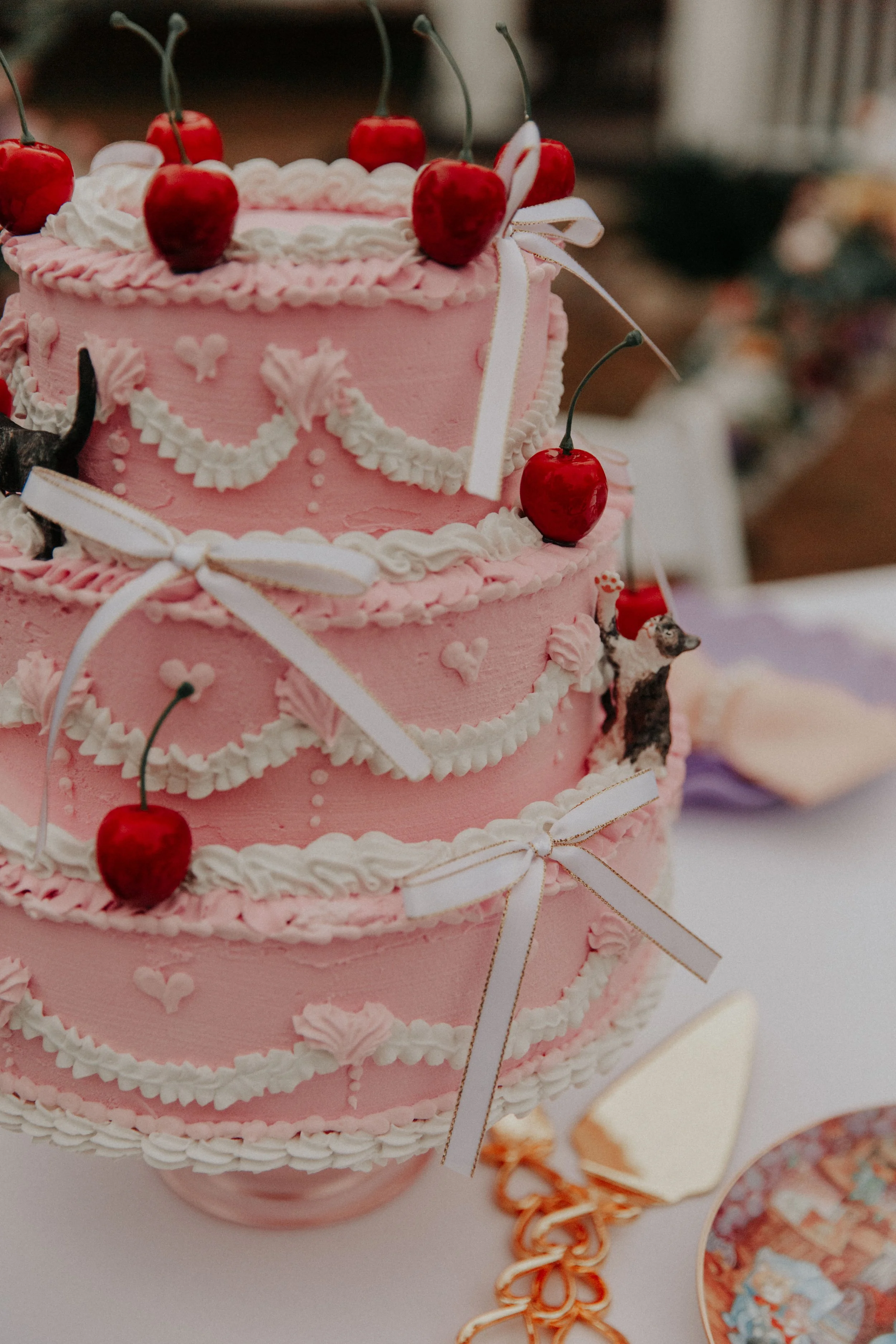 Pink vintage-inspired wedding cake with cherries, bows, and whimsical retro piping details for colorful alternative wedding