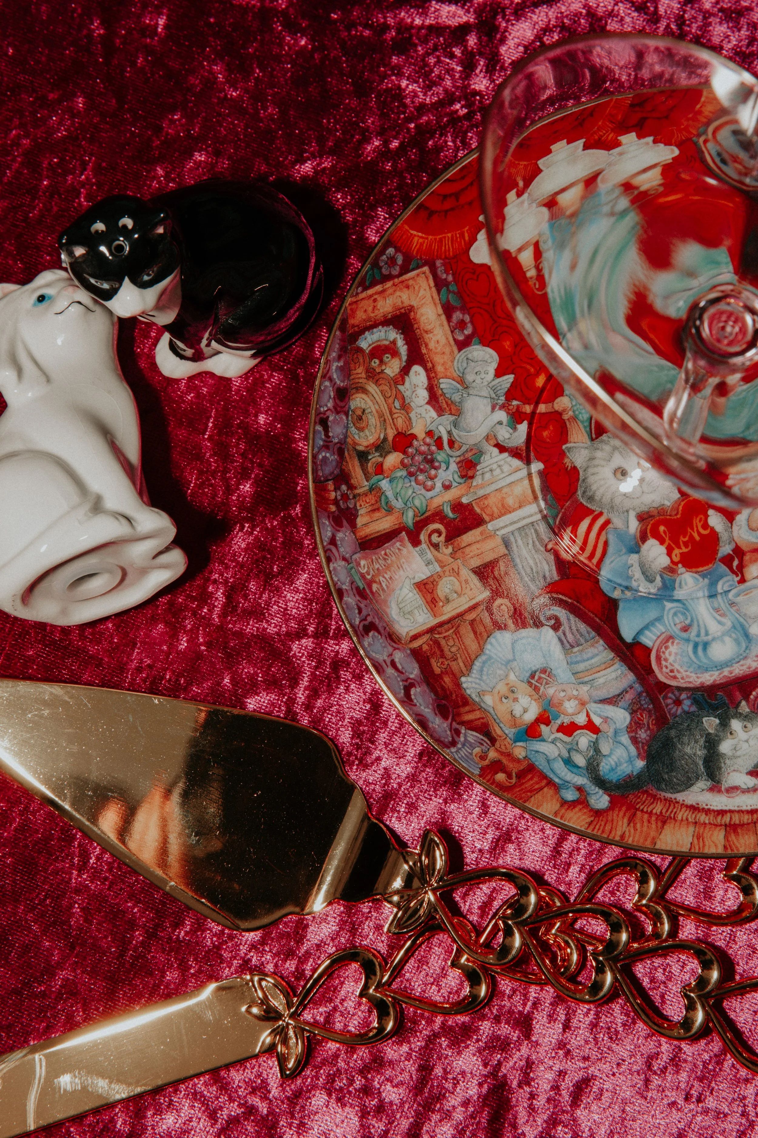 Vintage-inspired kitschy wedding table details with velvet linens, heart-handled cake server, and whimsical cat-themed plate