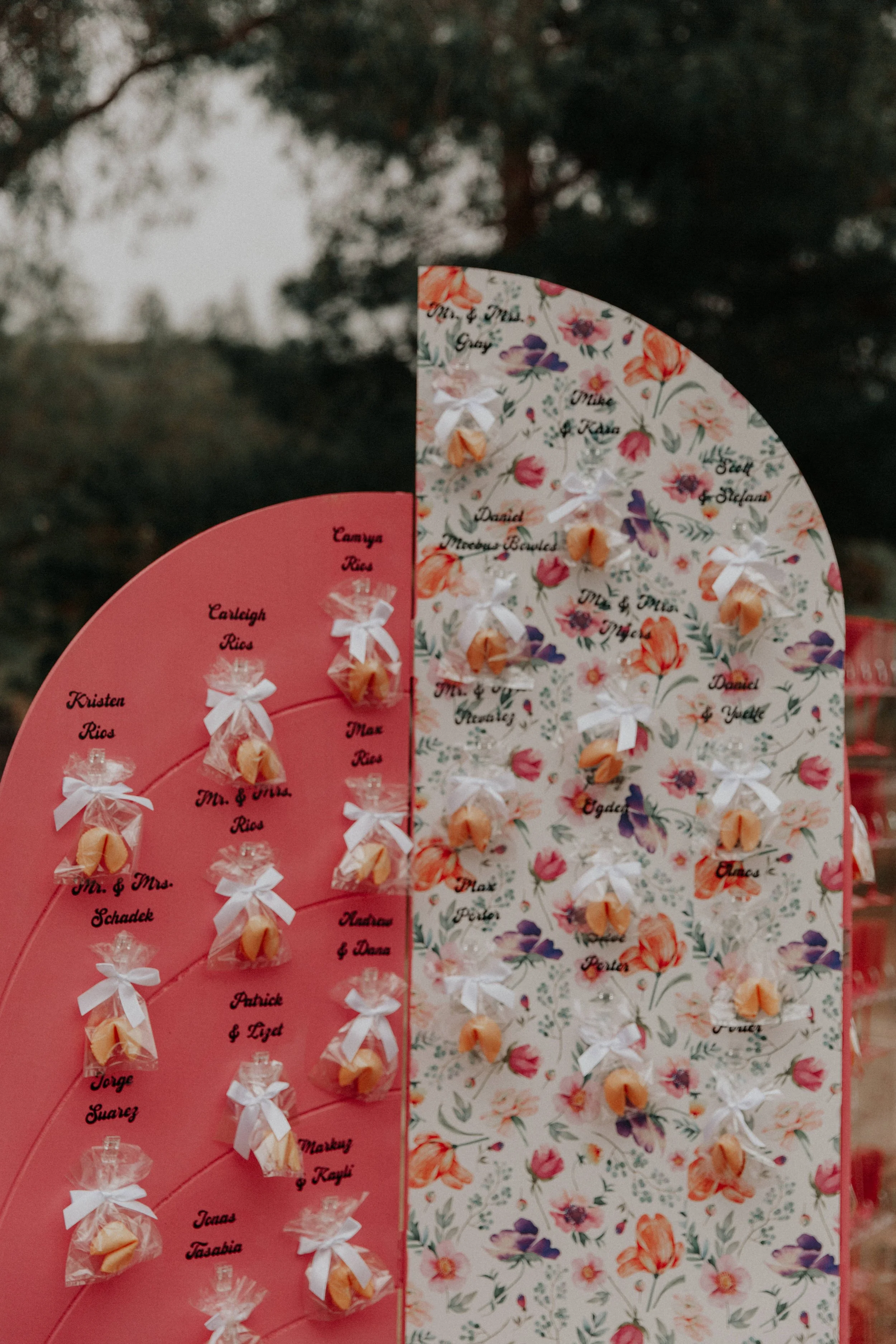 Floral and pink fortune cookie seating chart display at colorful whimsical wedding reception