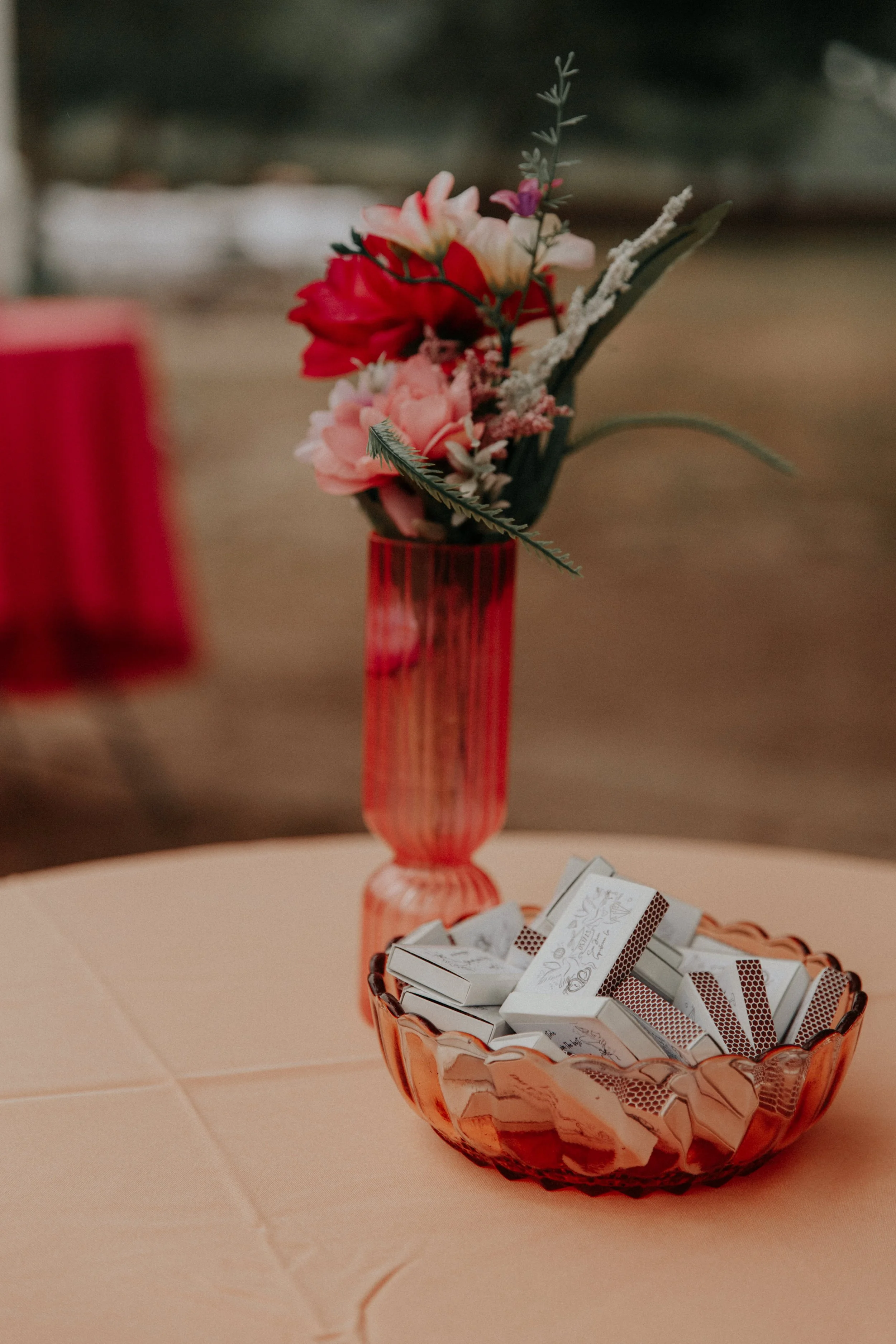 Retro-inspired wedding reception centerpiece with pink glass vase and custom matchbook favors