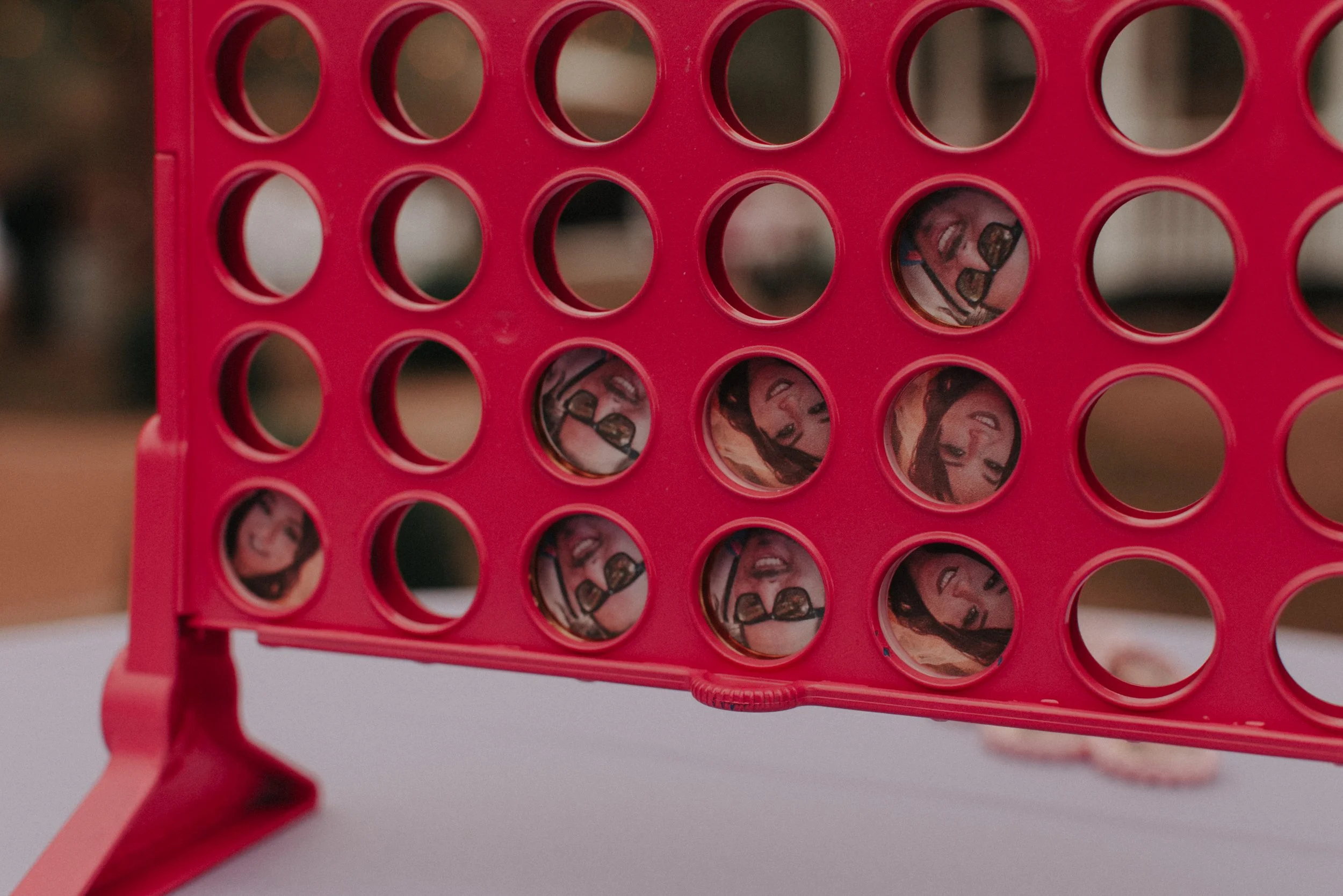 Close-up of red Connect Four wedding game featuring custom photo tokens of the bride and groom
