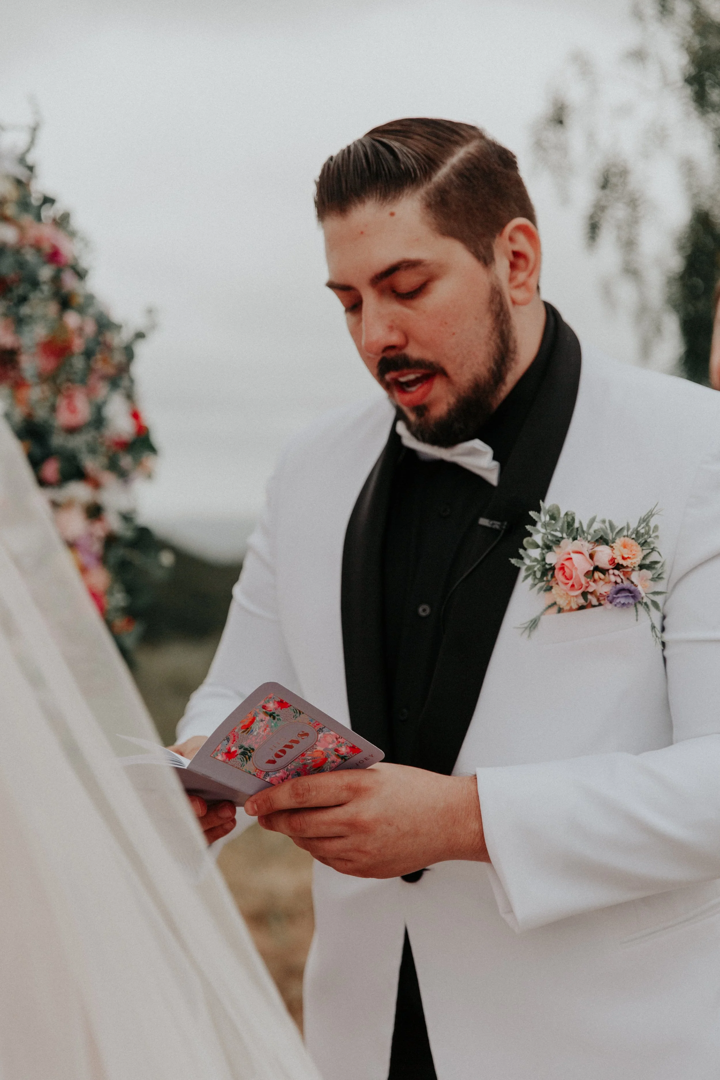 Groom reading handwritten vows during romantic outdoor wedding ceremony