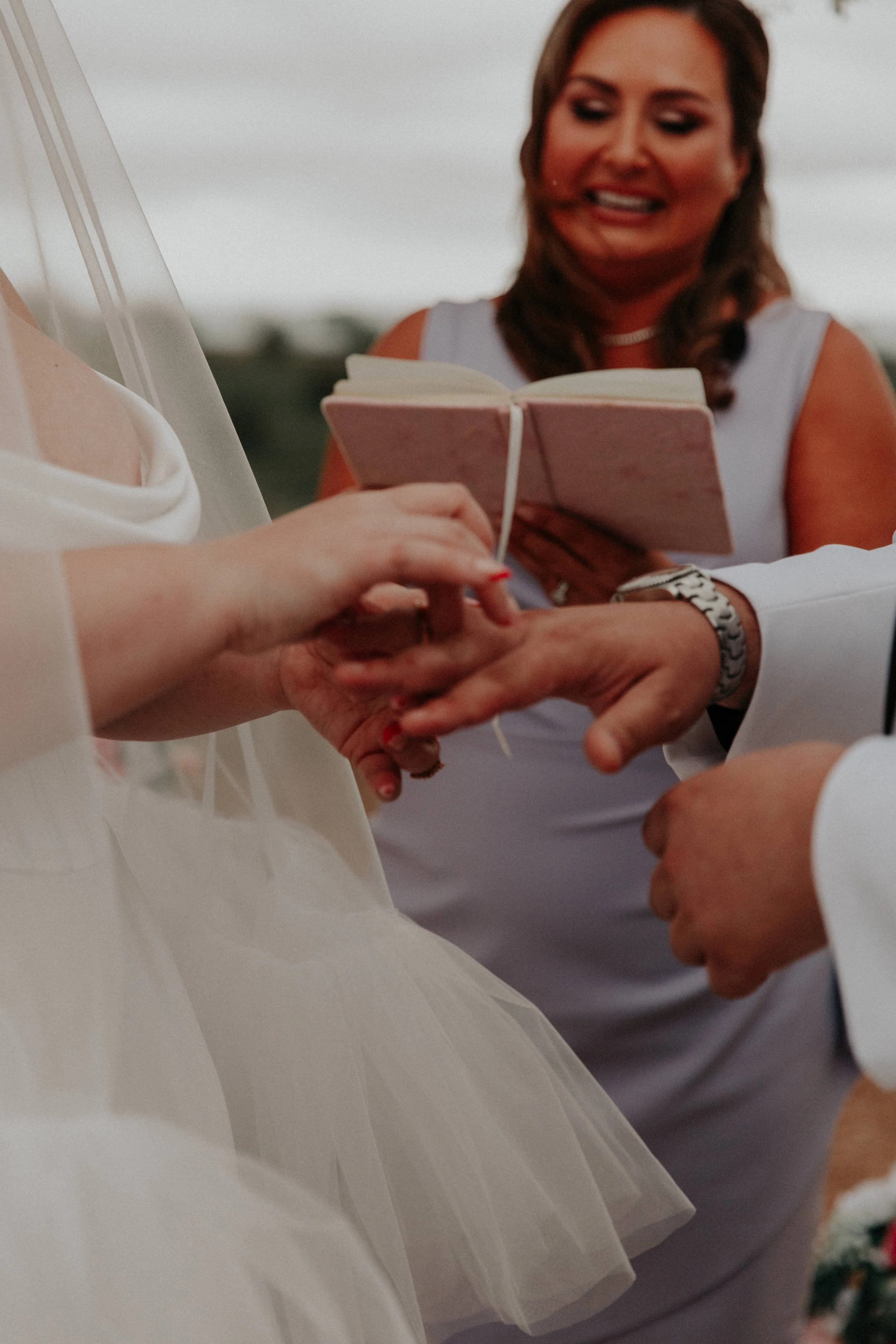 Close-up of bride placing wedding ring on groom’s finger during ceremony