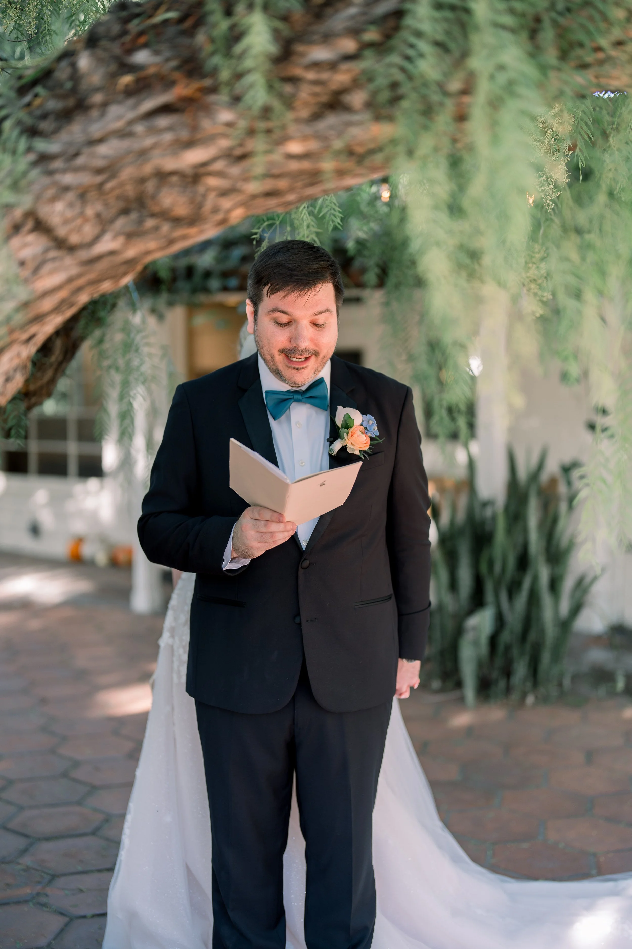 Groom reading handwritten vows during a private first look moment before the wedding ceremony