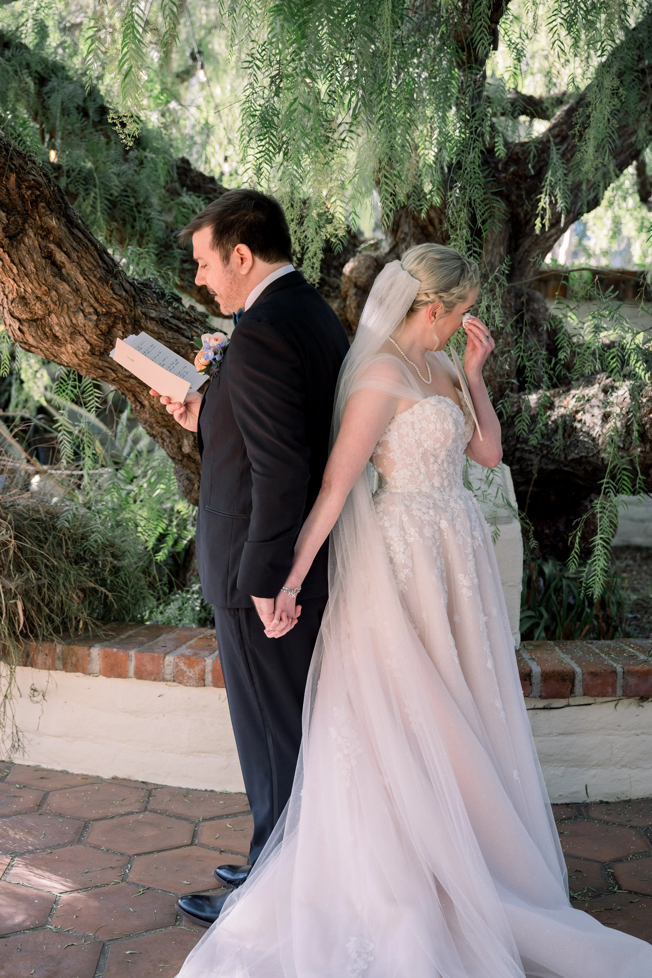 Bride wiping away tears while listening to the groom read private vows before the ceremony