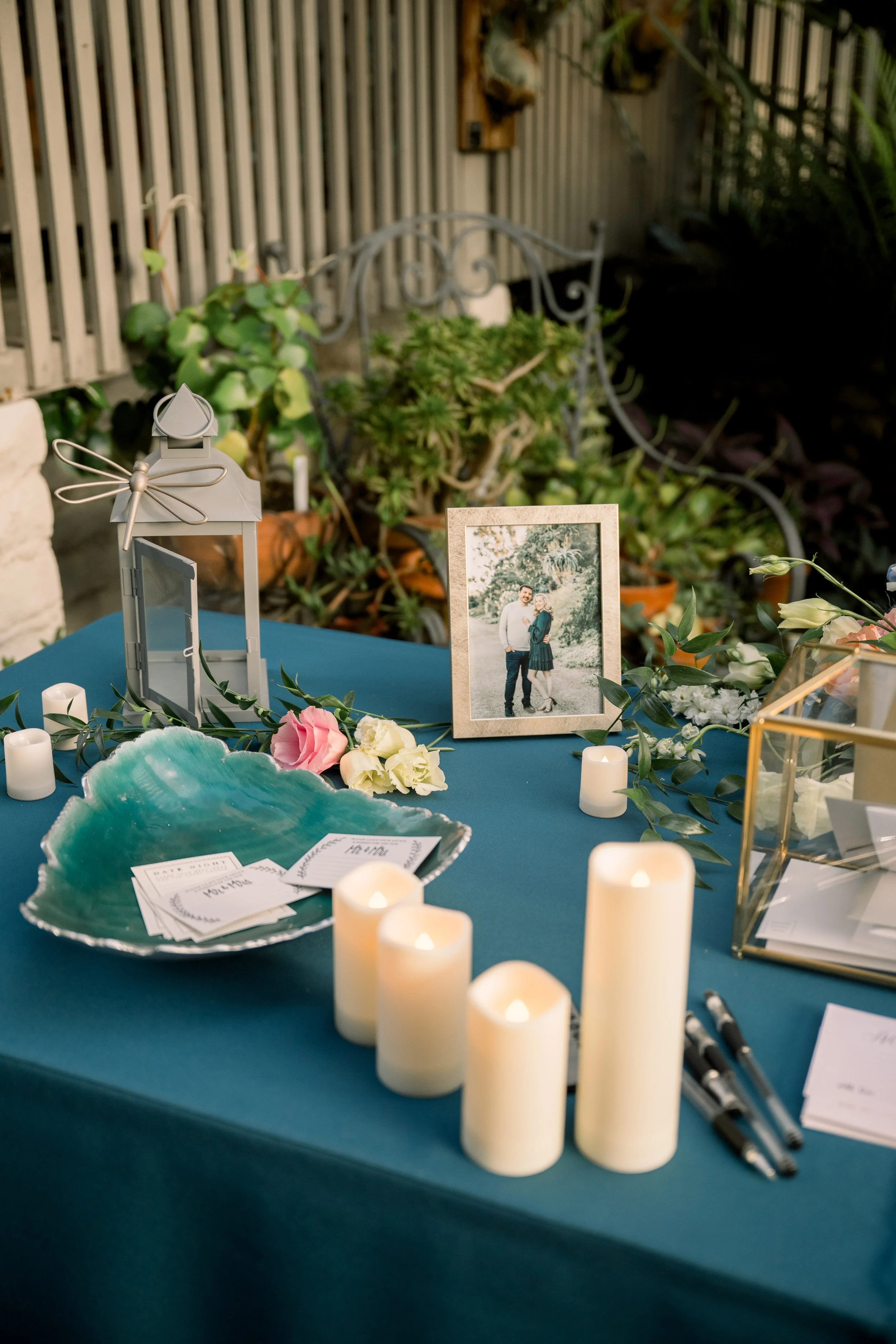 Teal tablecloth with peach, blush, blue, and ivory blooms arranged on a gift table