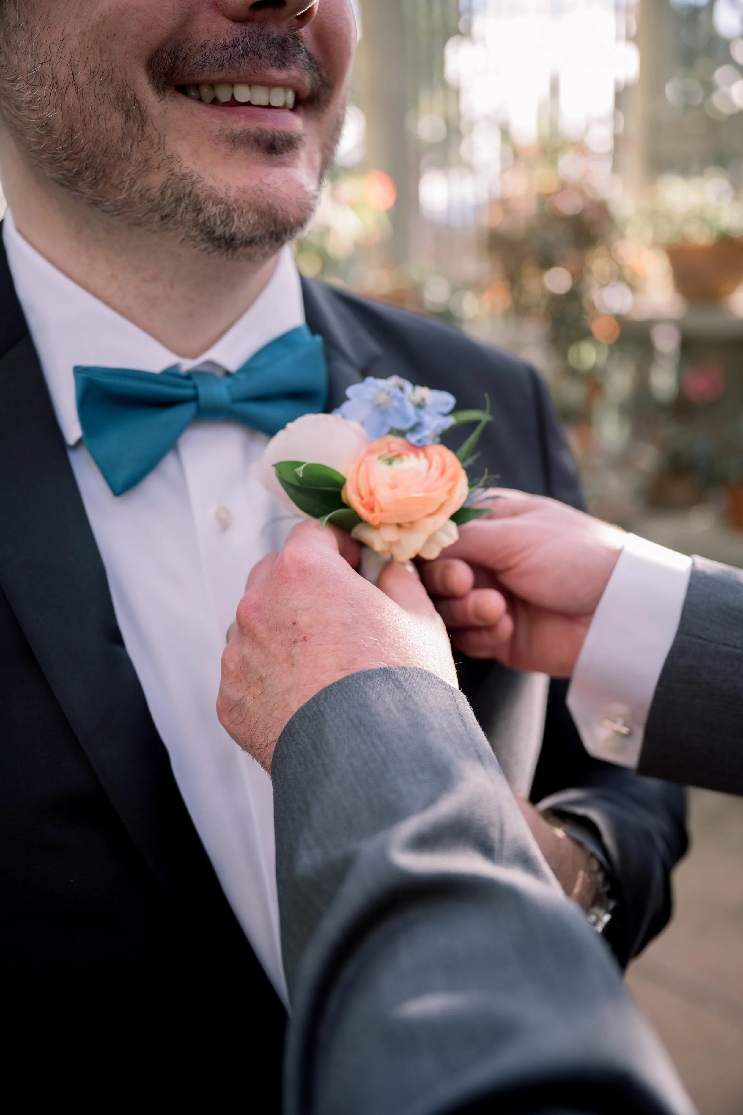 Close-up detail of a groom’s boutonniere being adjusted before the wedding ceremony