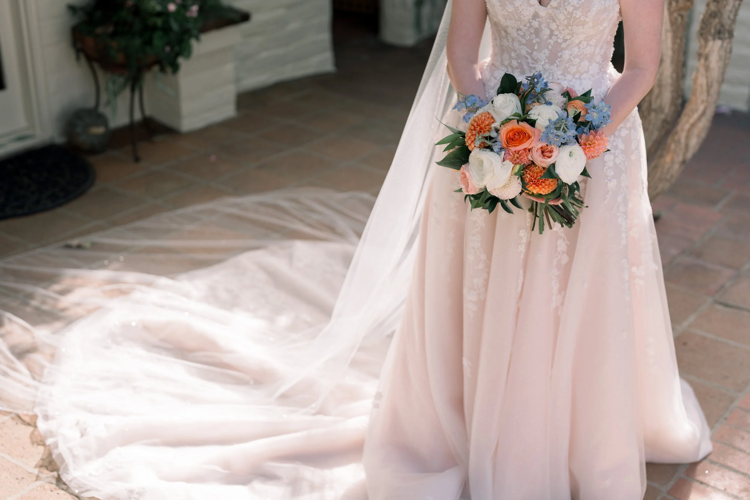 Close-up detail of the bride’s bouquet, wedding gown, and flowing veil during bridal portraits