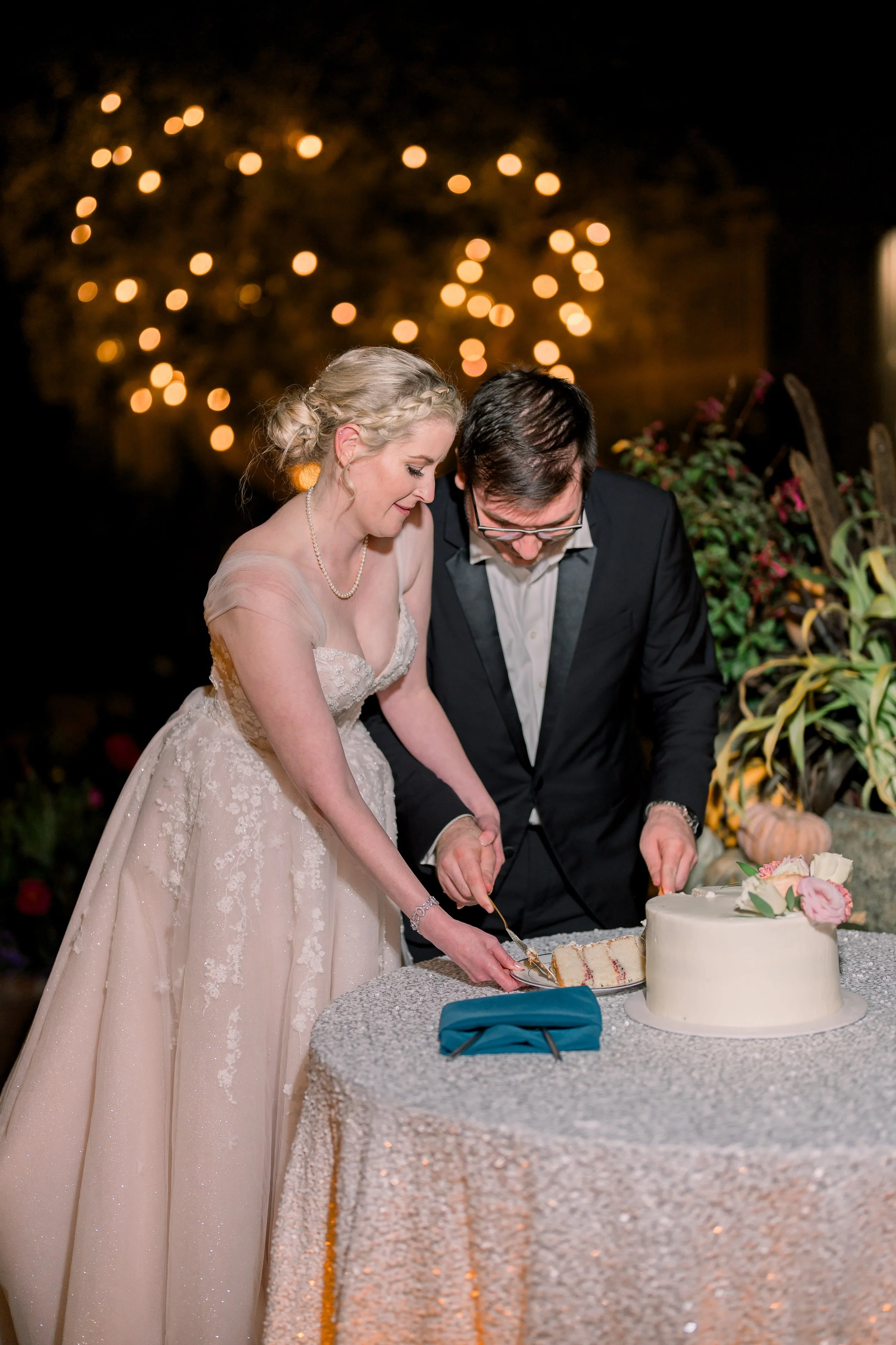 Bride and groom cutting and serving wedding cake together during the evening reception