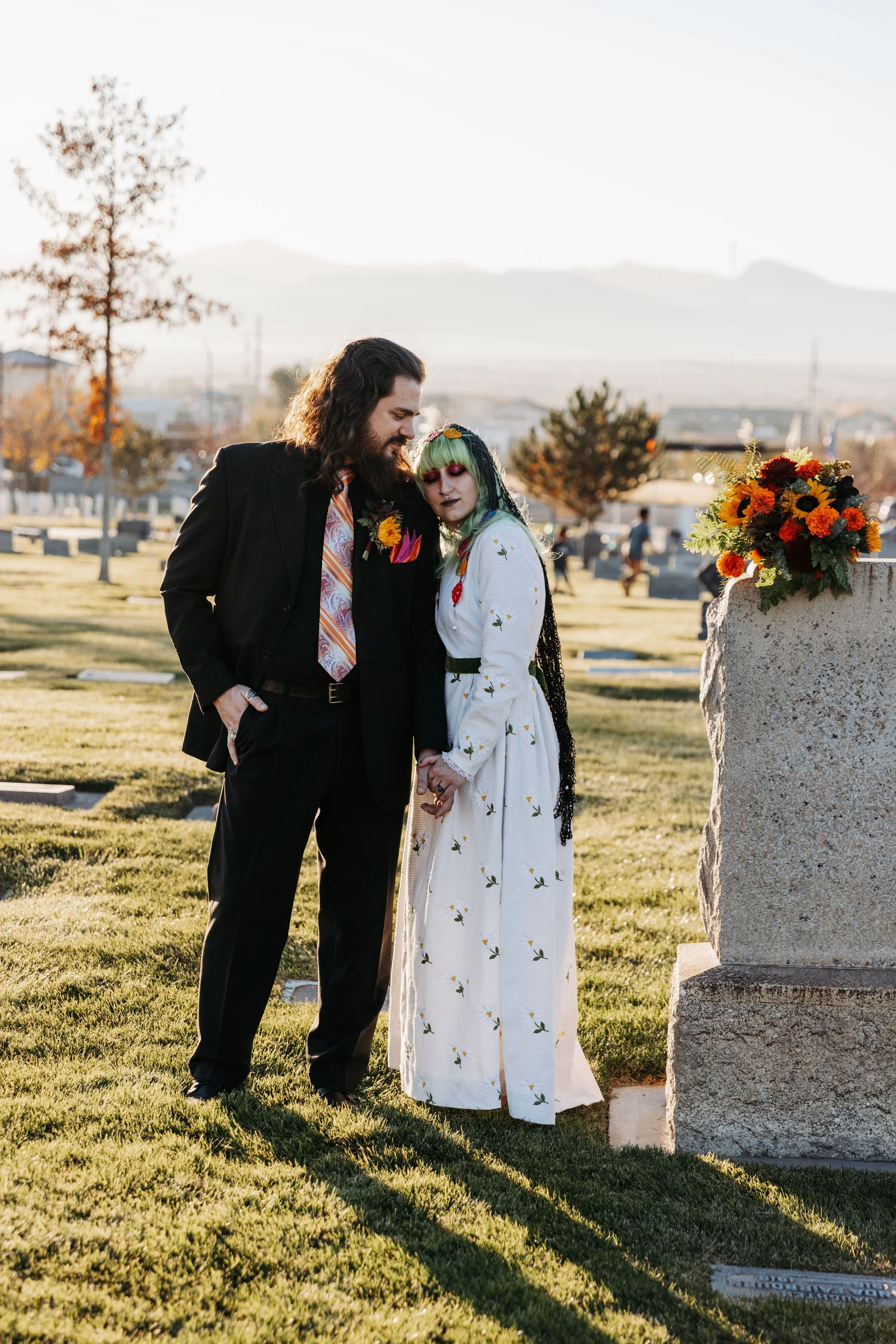 Couple standing together in a cemetery during golden hour portraits, incorporating meaningful and nontraditional elements into their Día de los Muertos wedding celebration.