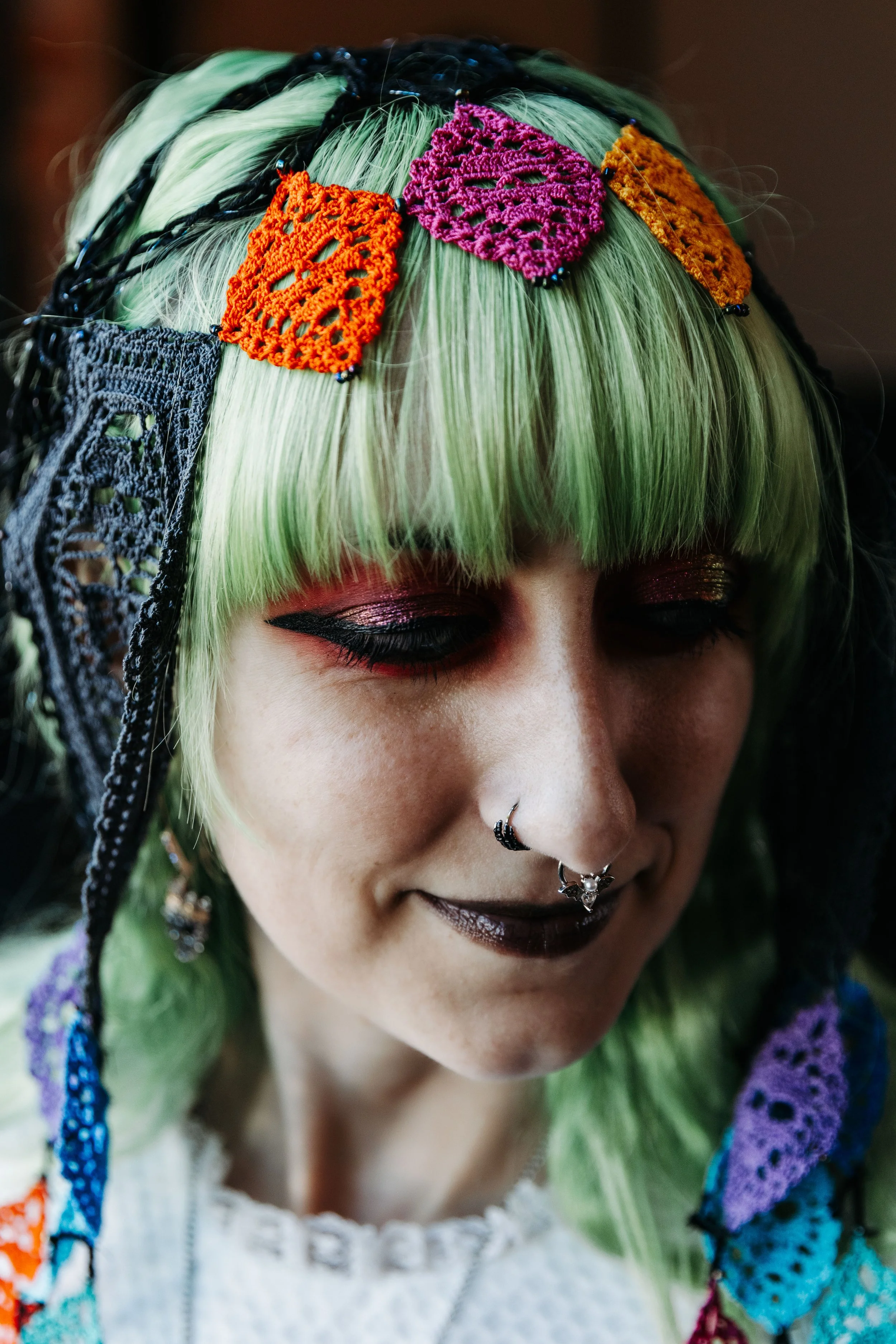 Close-up bridal portrait highlighting colorful lace hair accessories, mint green hair, dramatic makeup, and unique alternative wedding style.