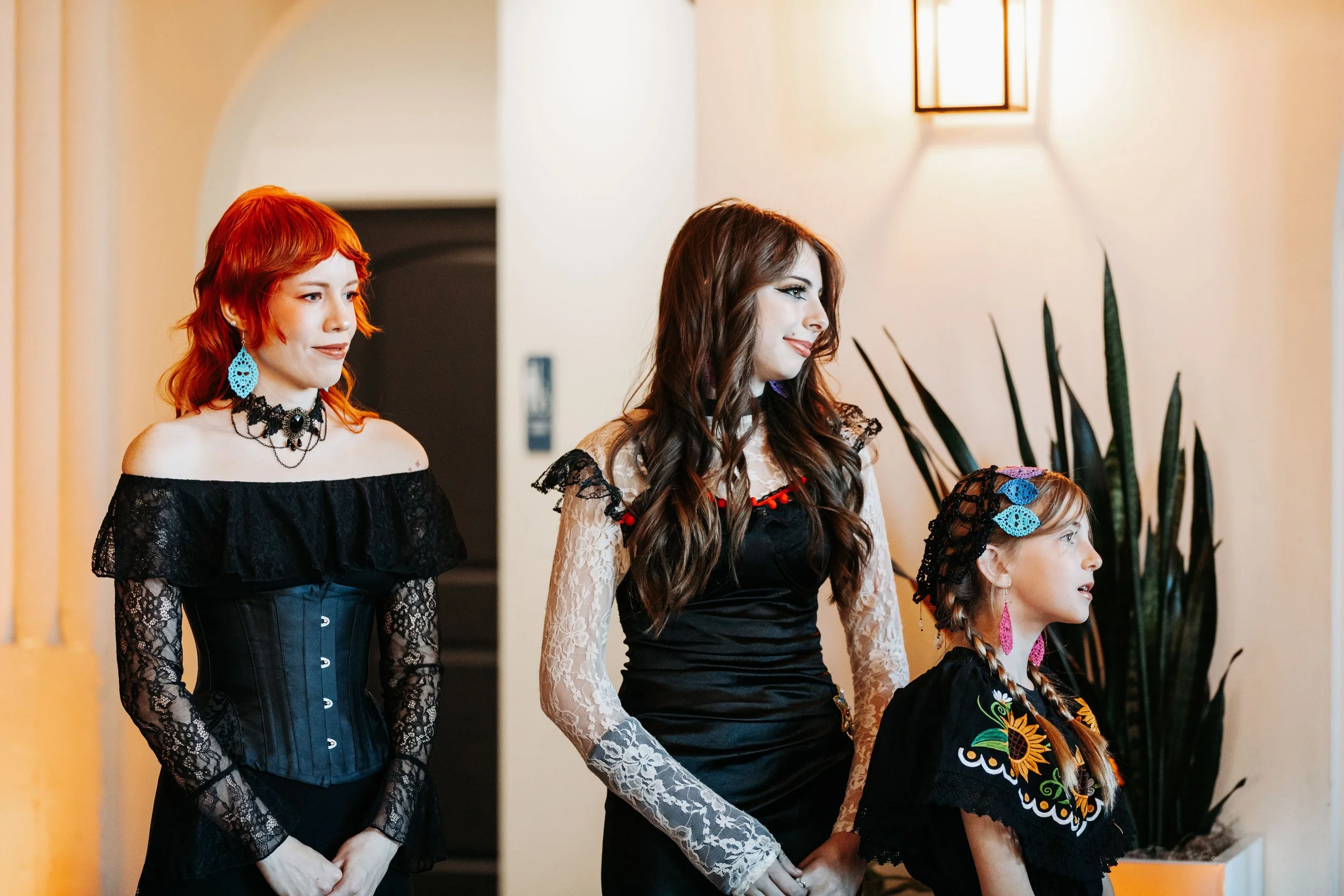 Members of the wedding party watch the ceremony, wearing coordinated alternative wedding attire inspired by Día de los Muertos and gothic styles.