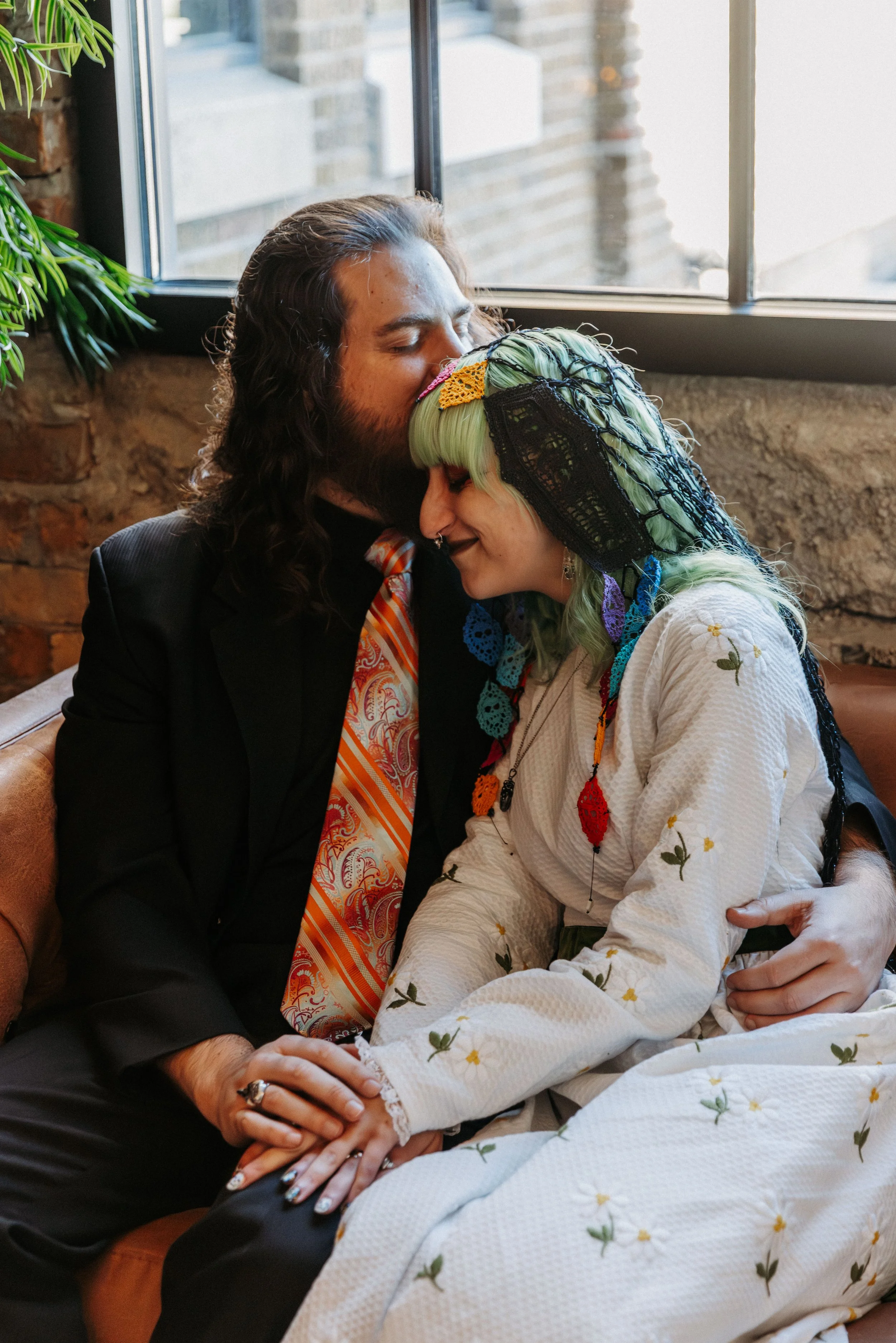 Bride and groom share a quiet moment together on a vintage sofa inside Crescent Hall before their nontraditional wedding ceremony.